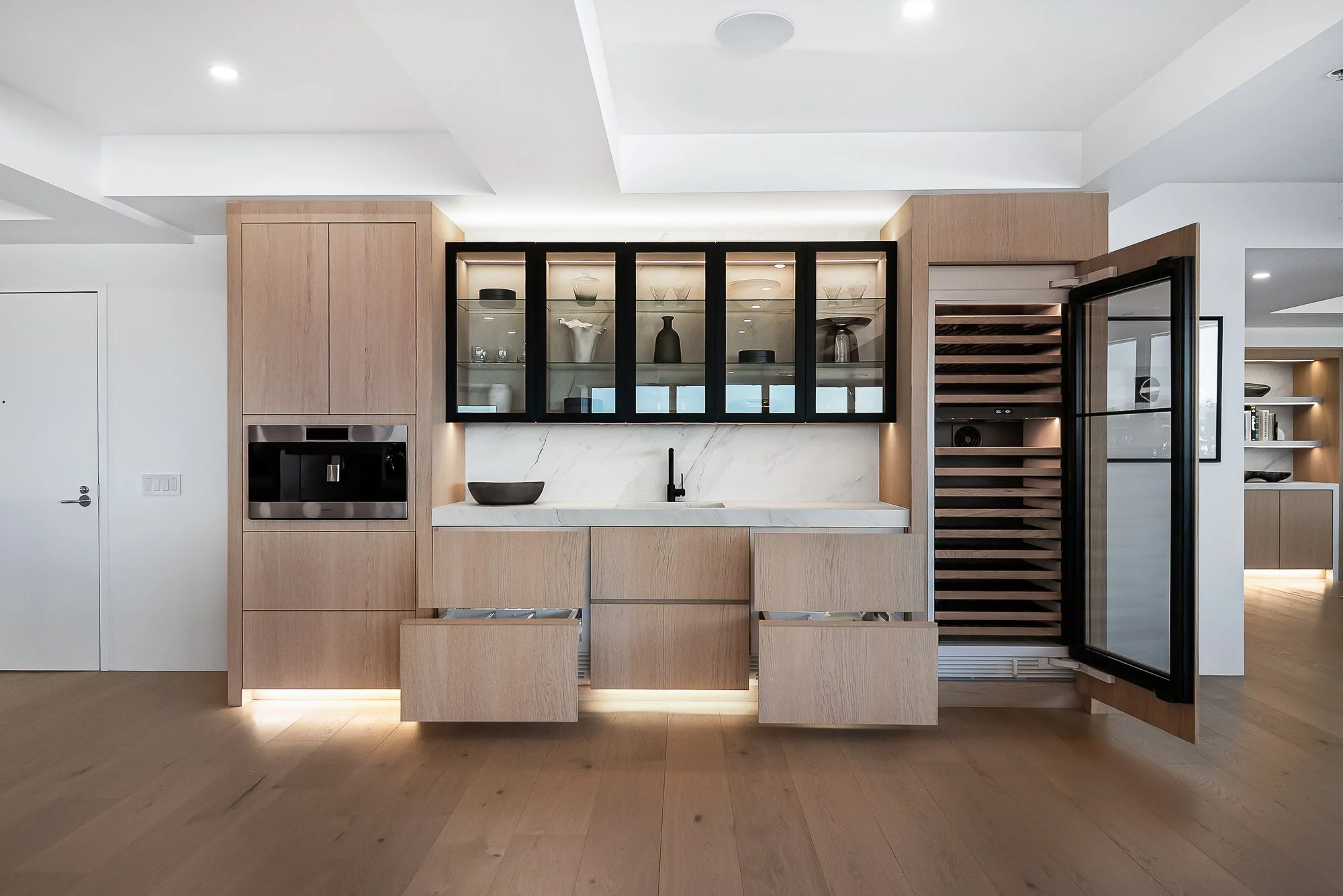 Elegant white oak dry bar with panel-ready wine and beverage coolers, glass cabinets, and built-in storage for barware and bottles