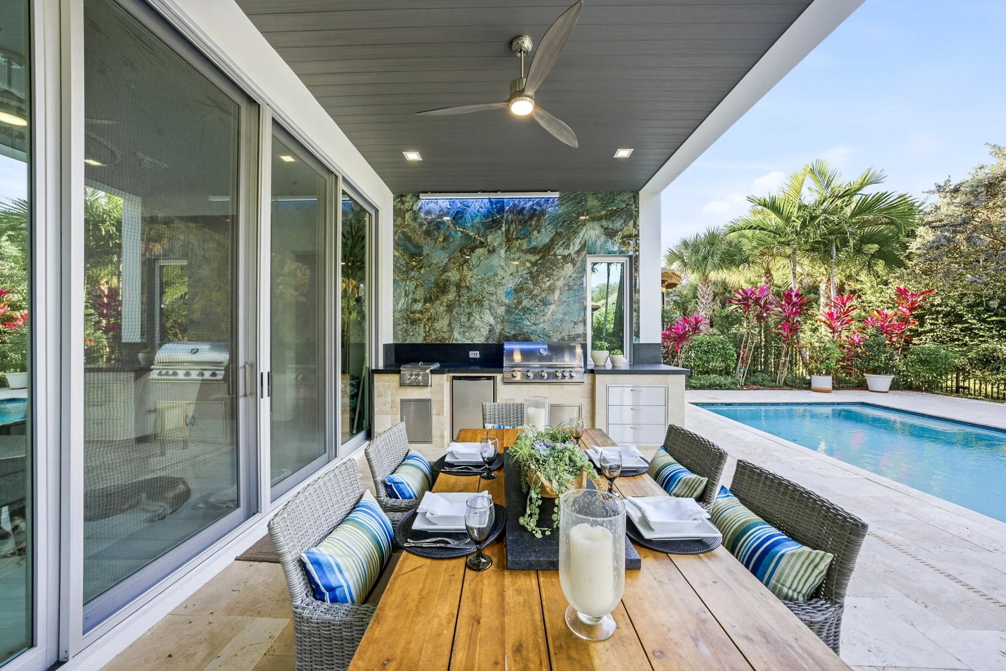Outdoor kitchen with grill, power burner, granite counter, travertine facing and floor, stone backsplash, composite plank ceiling
