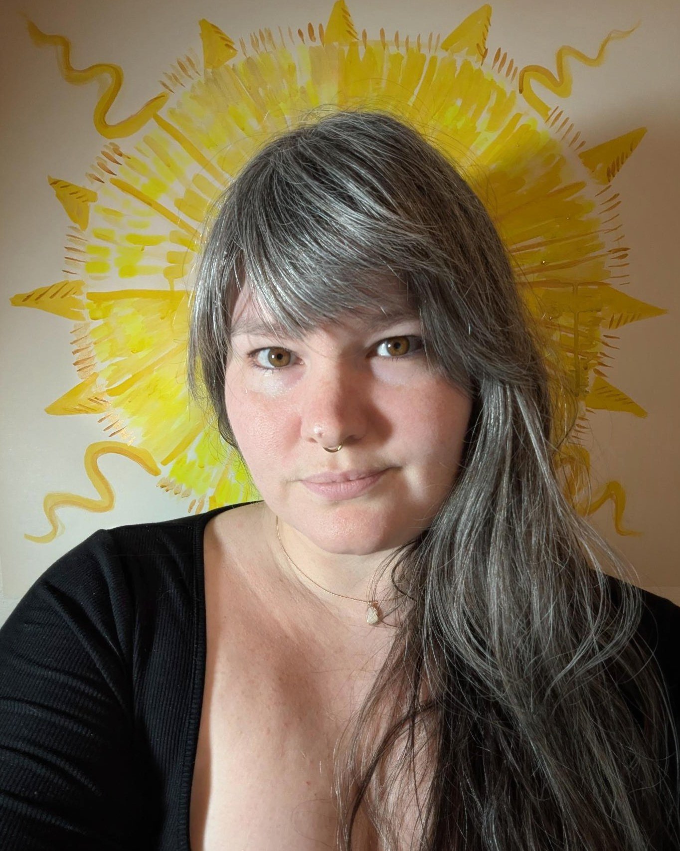 A woman with long hair and a septum piercing against a yellow sun. A tarot reader and astrologer in Baltimore, MD available for private parties and corporate events. Schedule a tarot reading or birth chart reading with Clear Eyes Divination.