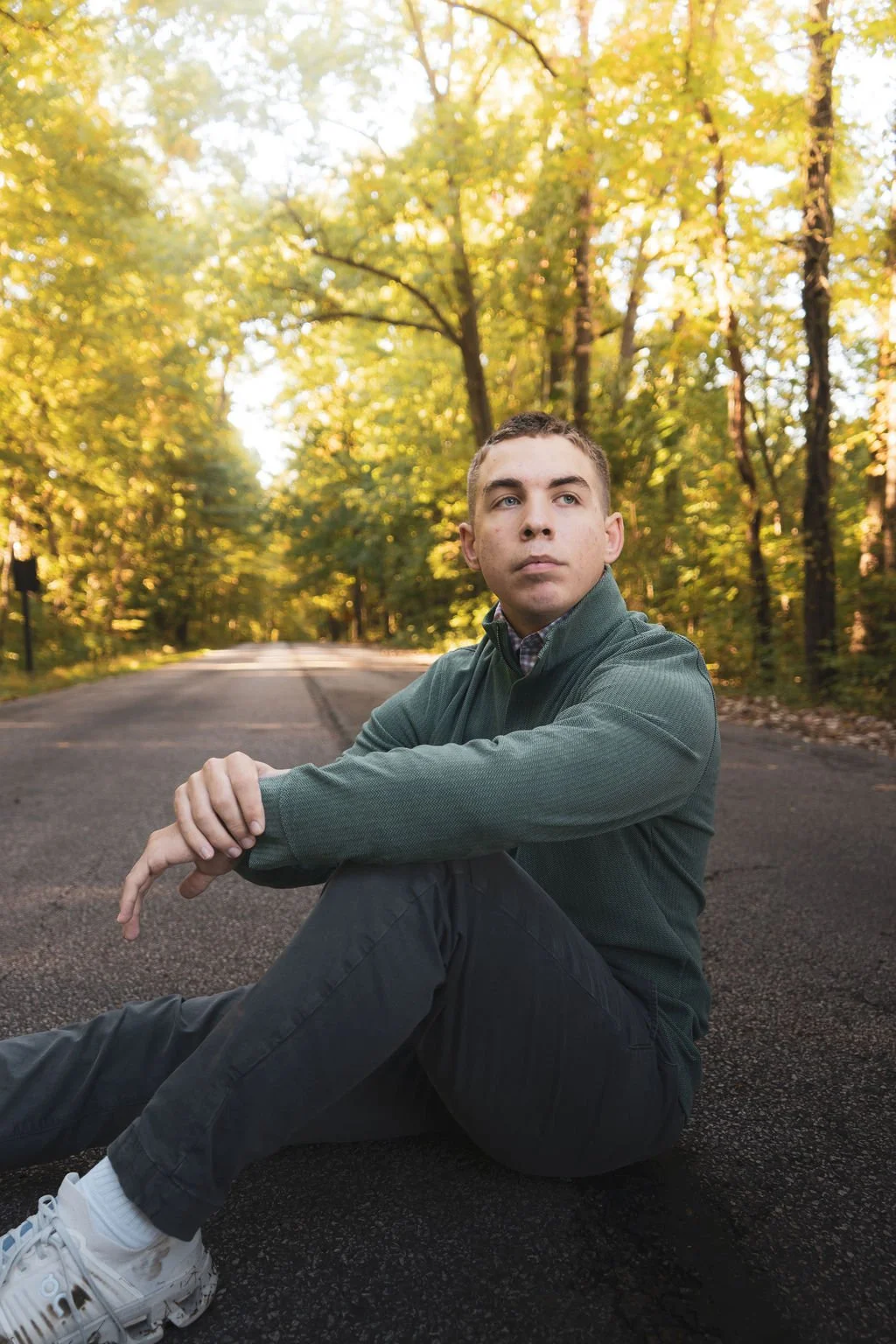 Outdoor senior portrait of a young man seated on a wooded road in Cuyahoga Valley National Park