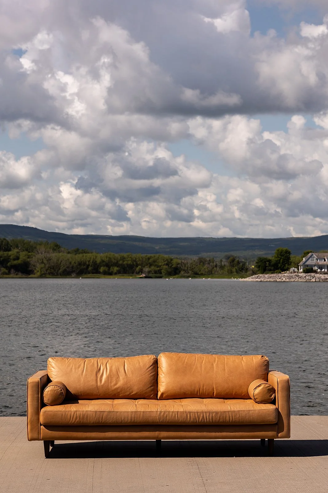 Tan leather sofa on a concrete surface by a lake with cloudy sky in the background in collingwood ontario for a real estate team. Town and county collective media agency