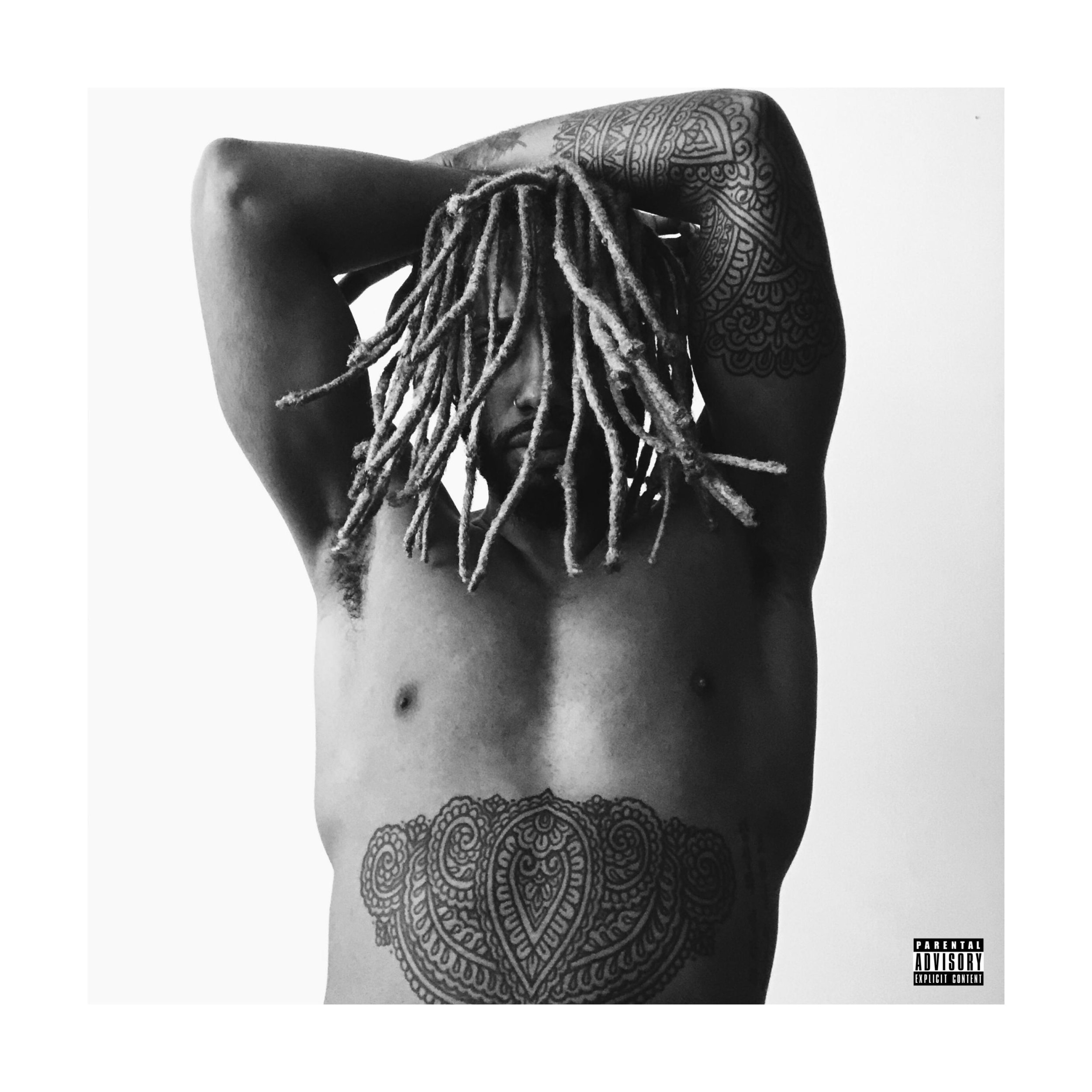 A shirtless person with dreadlocks, tattoos on arms and stomach, posing with arms raised and hands behind head, against a plain background.