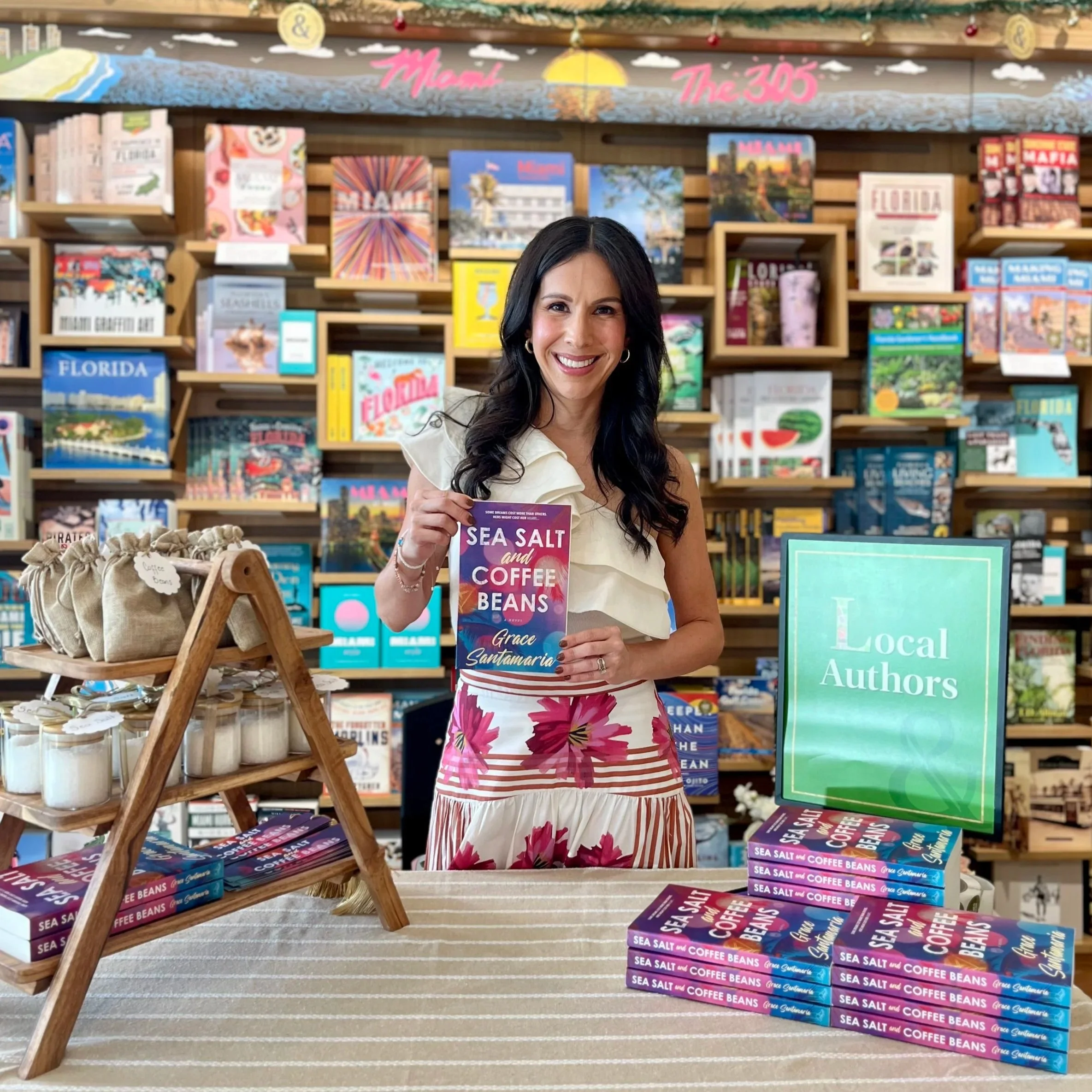 Grace Santamaria is holding a copy of her novel Sea Salt and Coffee Beans at a Barnes & Noble local author event