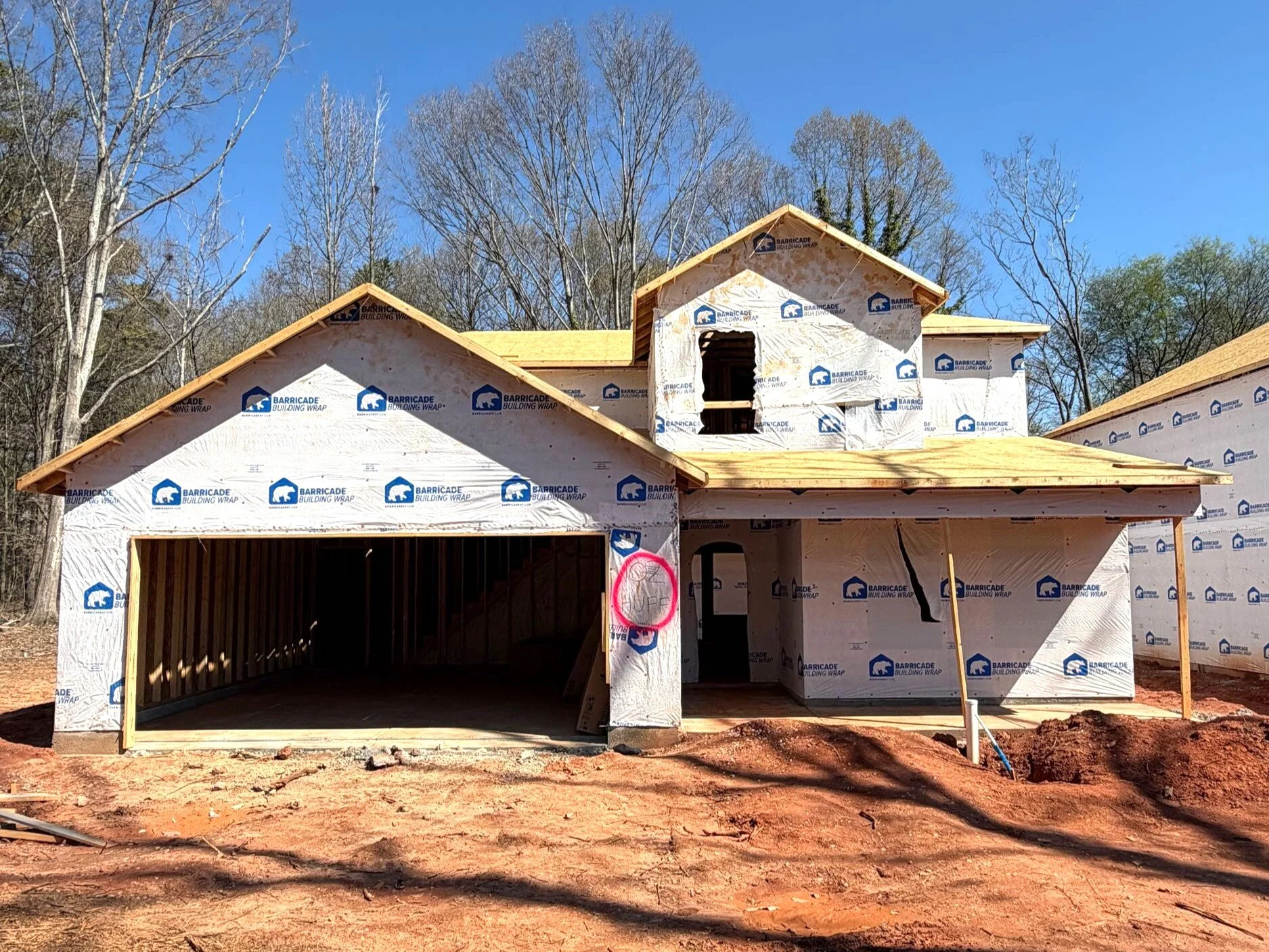 Architectural blueprint of a two-story house with a garage, front door, multiple windows, and detailed roof design.