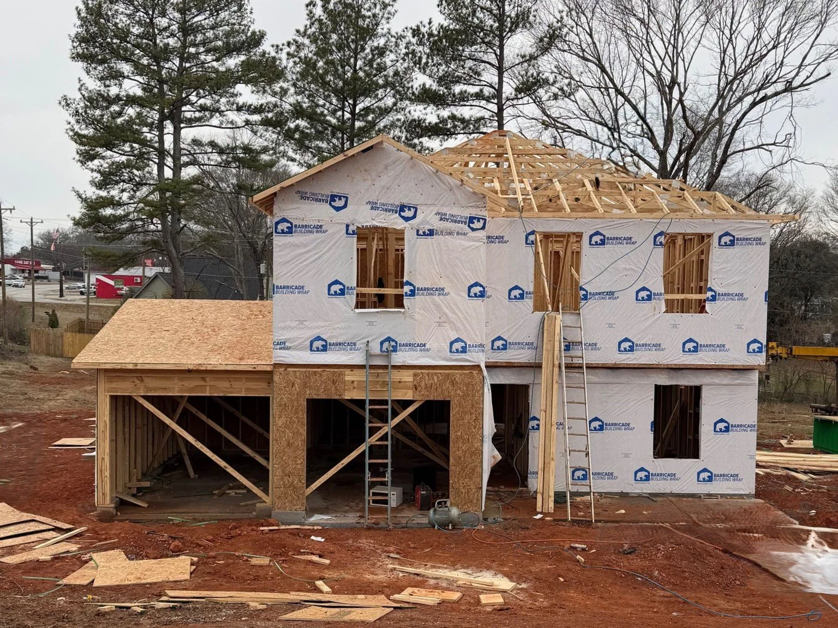 Concrete foundation slab at a construction site with surrounding trees and nearby houses.