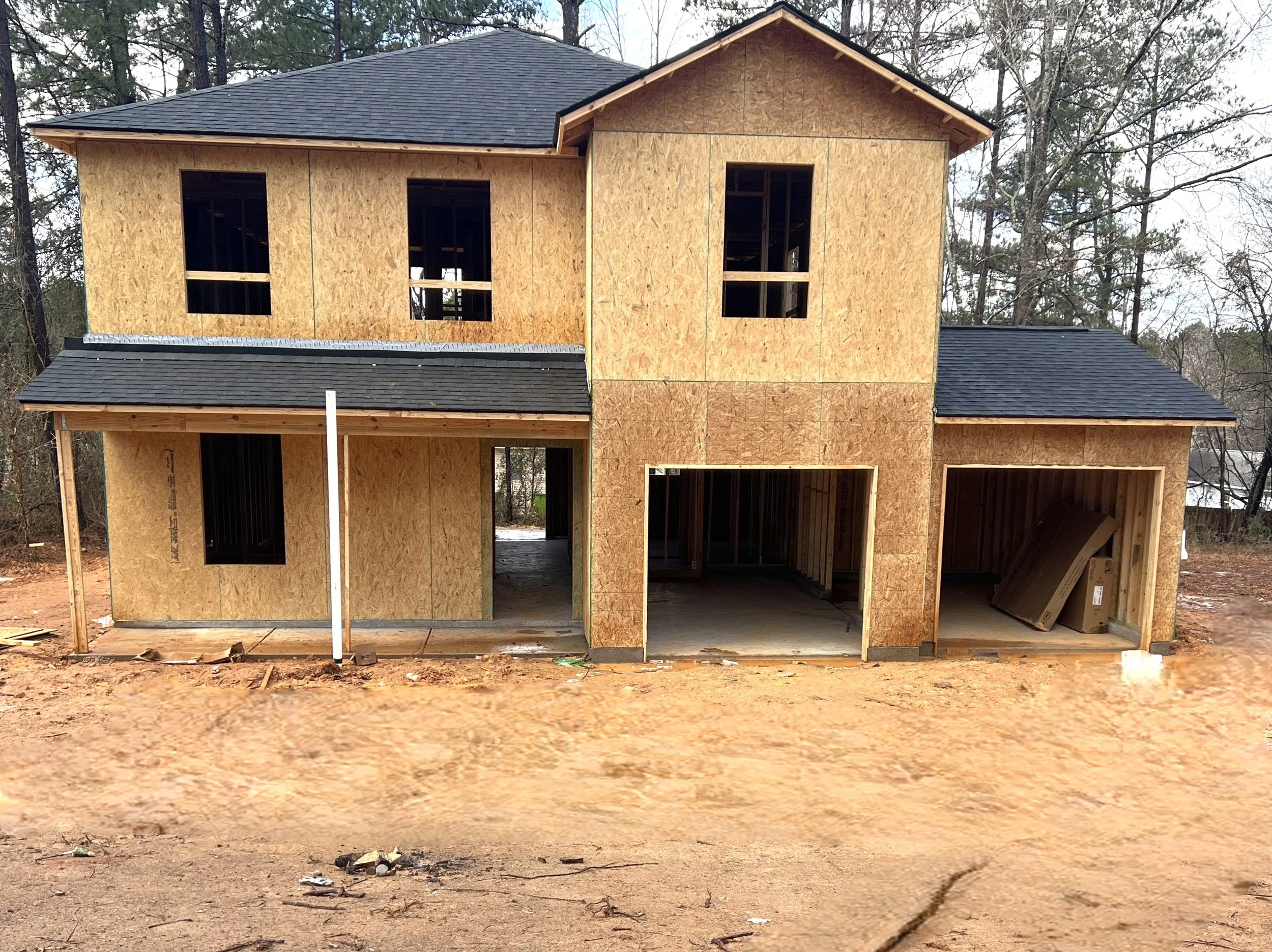 Concrete foundation slab at a construction site with surrounding trees and nearby houses.