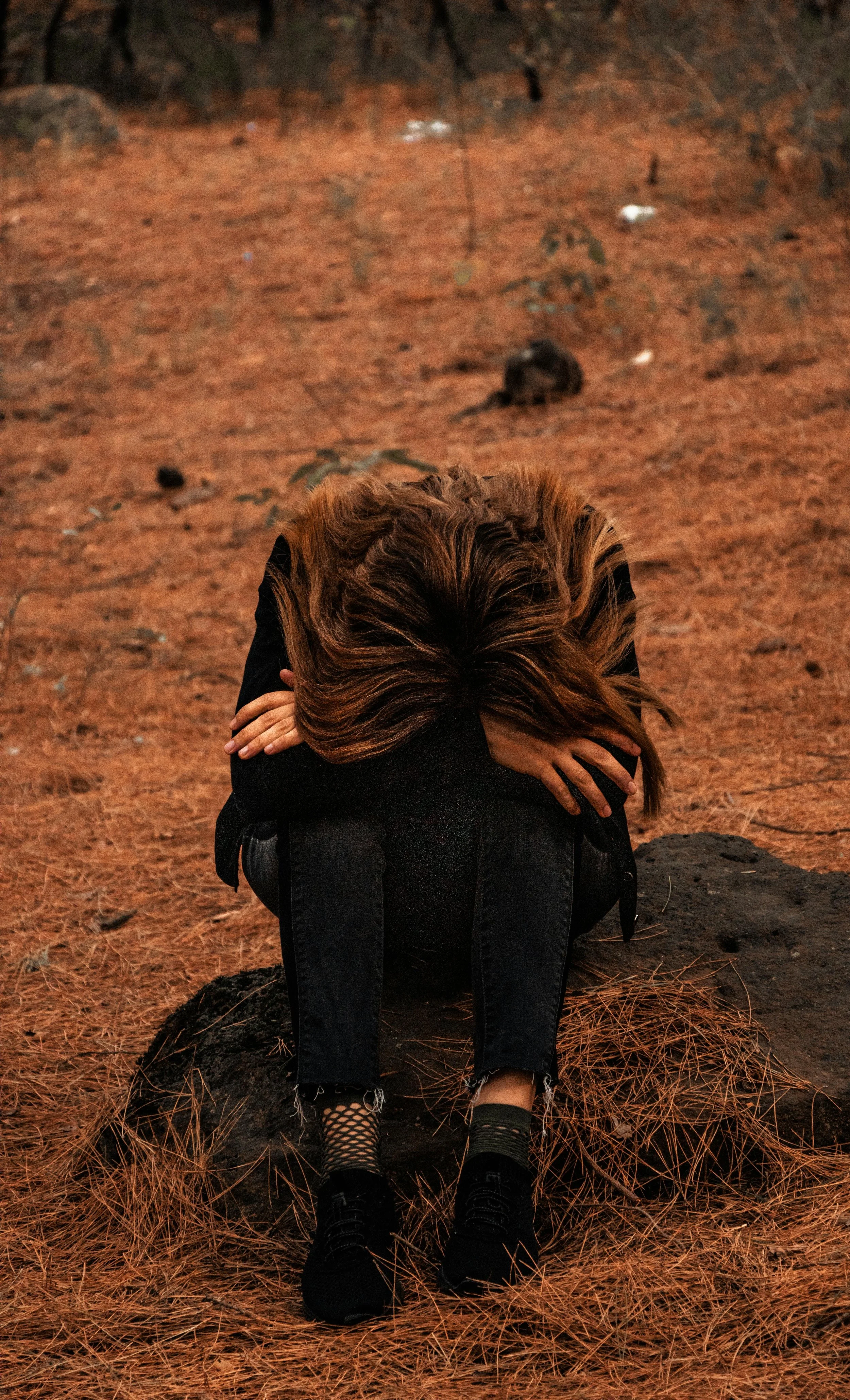 How Parasites Cause Depression and Anxiety Image of a Depressed woman in Nature with her head on her knees root cause healing with NIk Heartsong Winged Heart Healing