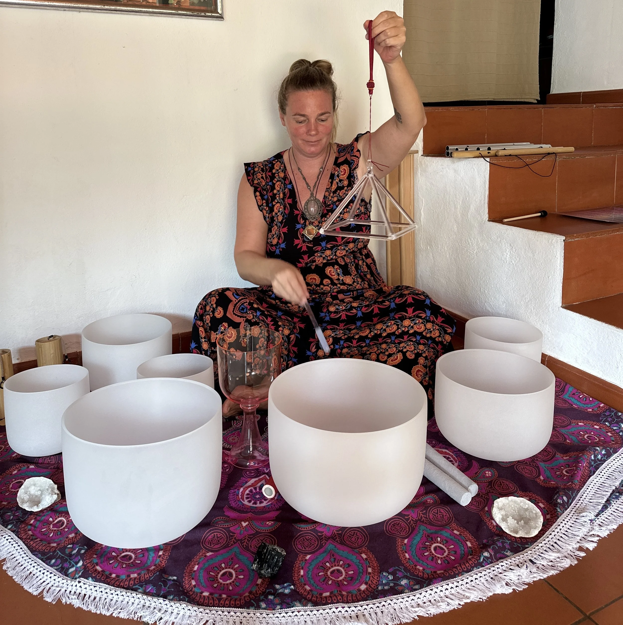 Nik Heartsong, bioresonance therapist and founder of Winged Heart healing. playing a crystal singing bowl chakra set with a mallet and crystal pyramid.