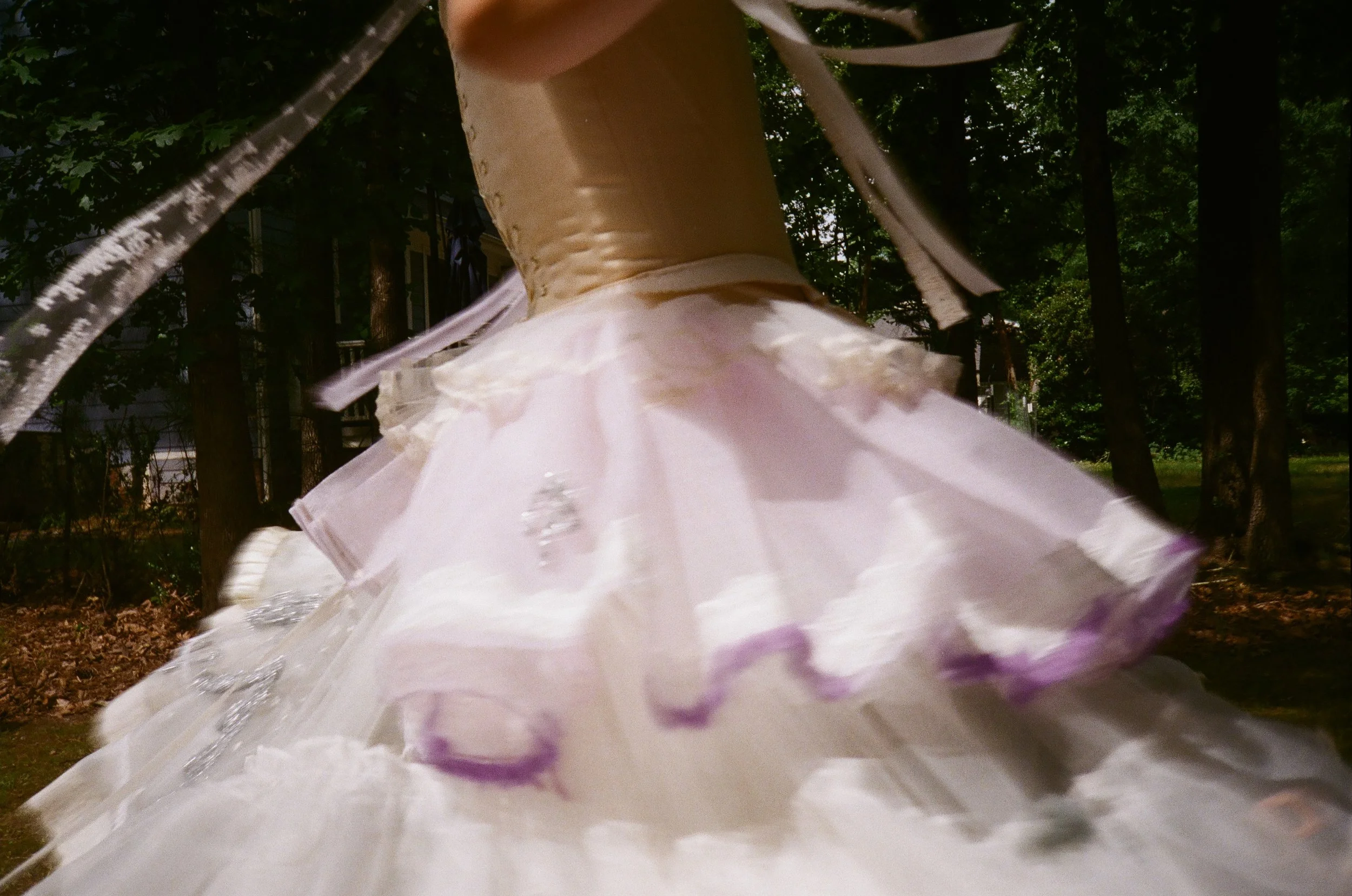 Close-up of a ballerina's tutu, focusing on the pink and purple fabric with embellishments, during a dance performance outdoors.