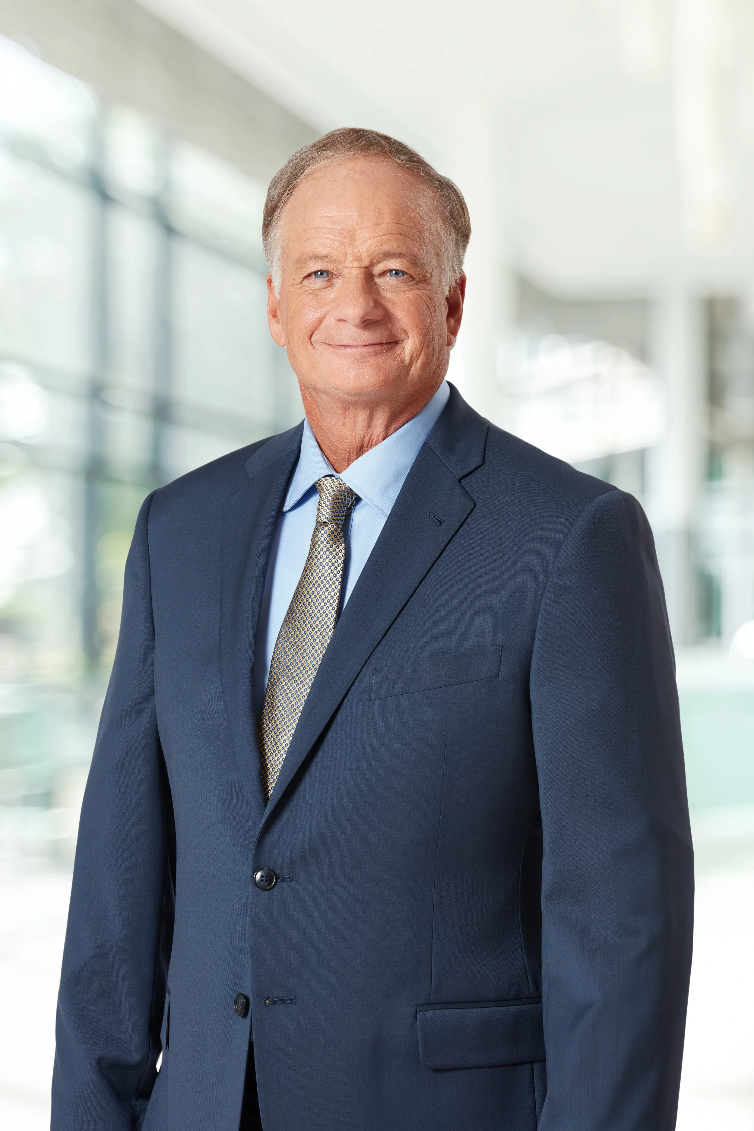 Headshot of Jim Perdue wearing a blue suit jacket, blue button down, and gray tie.