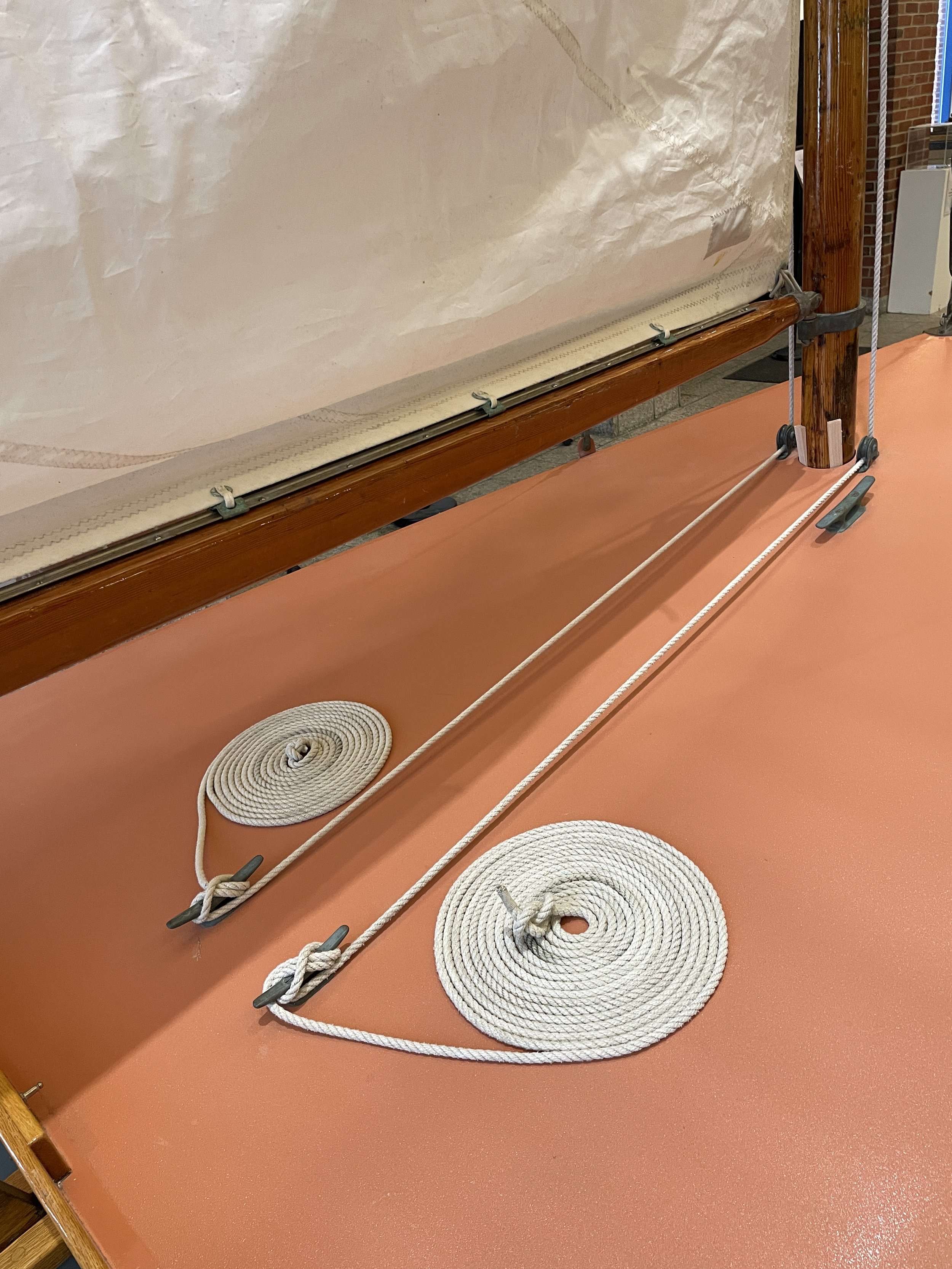 Gym equipment with ropes and circular mats on a red floor near a wooden and brick wall.