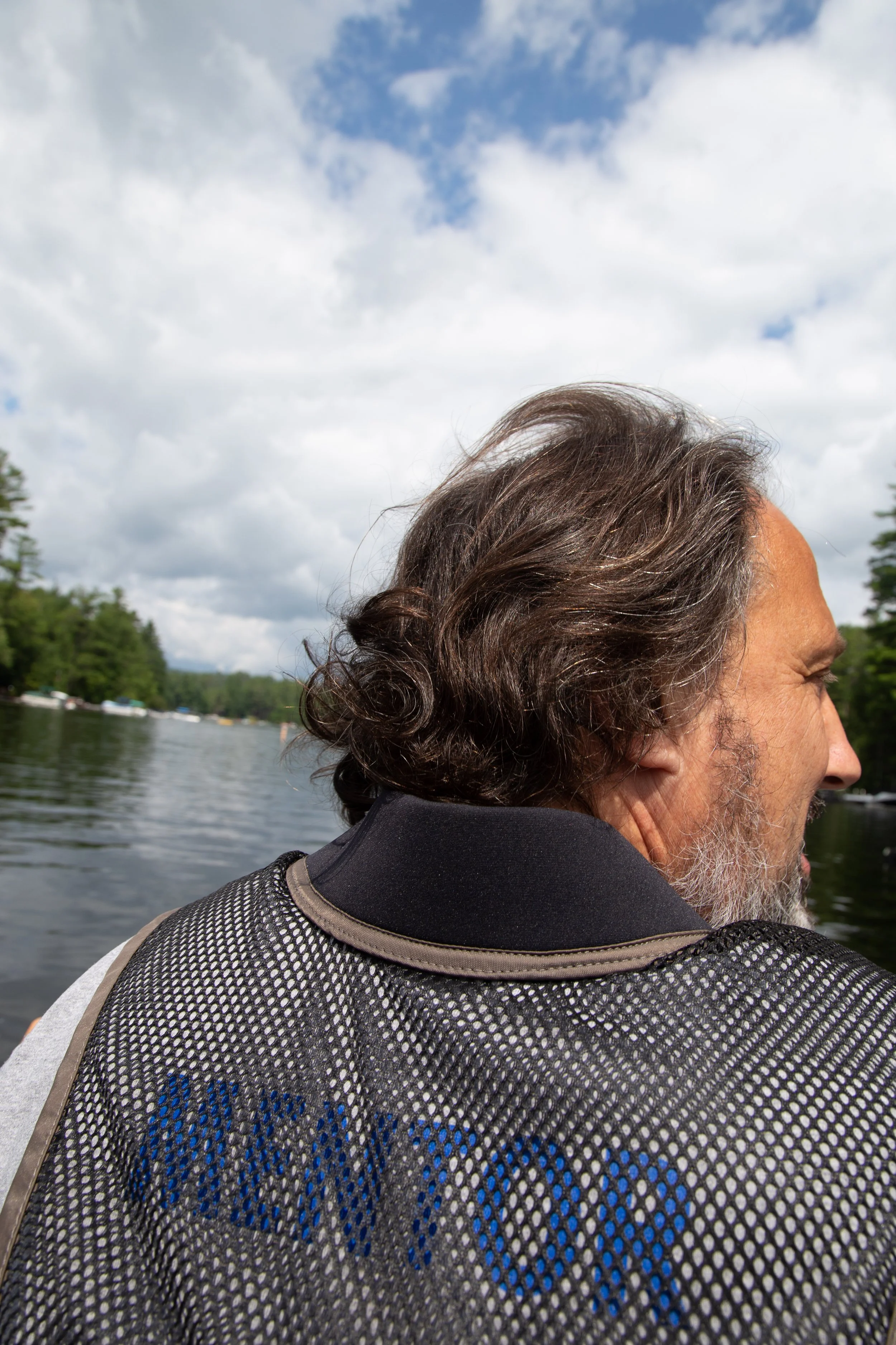 Back and side profile of Dr. Duncan, head of Camp Reece, in the water at Loon Lake with jacket that says Mentor on the back.