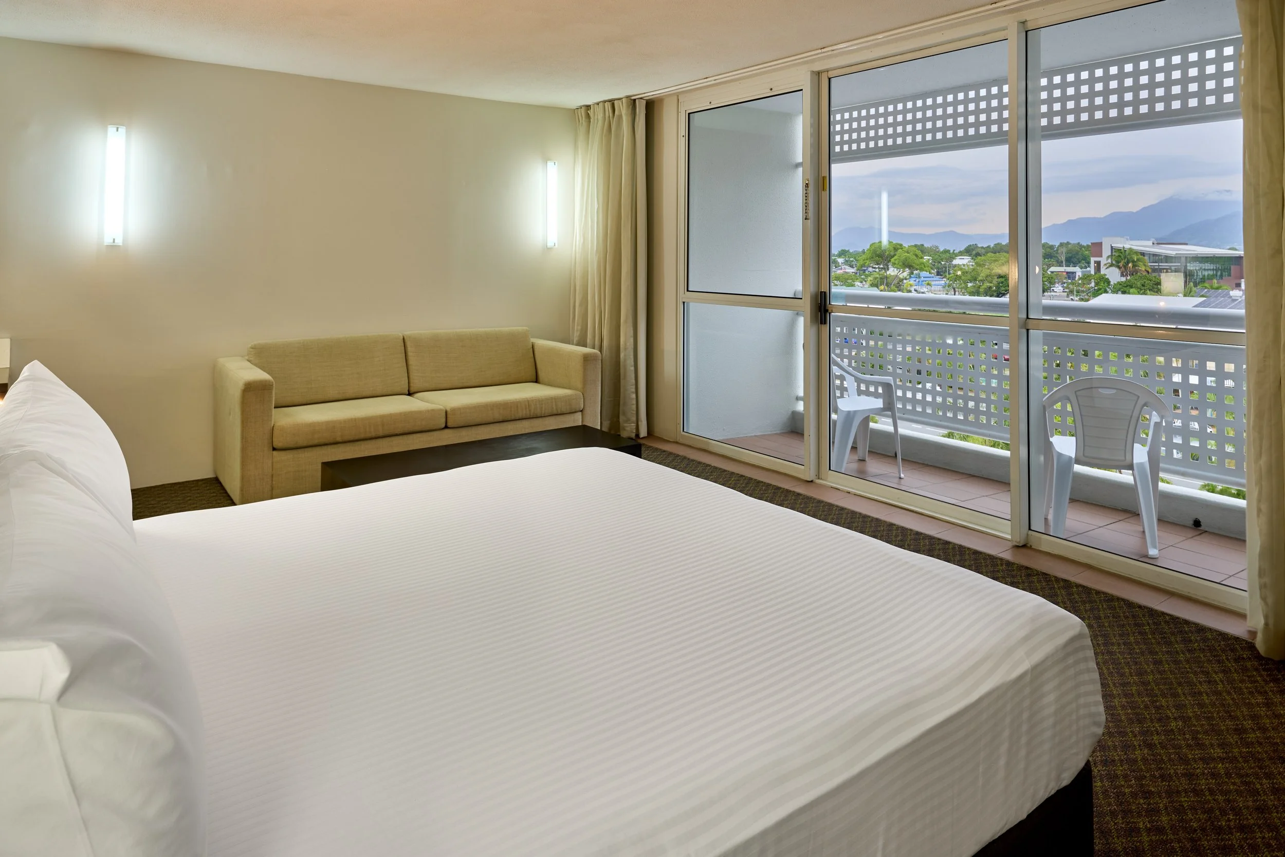 King bed with white linen, double sofa and view to private baclony with 2 chairs (1).jpg