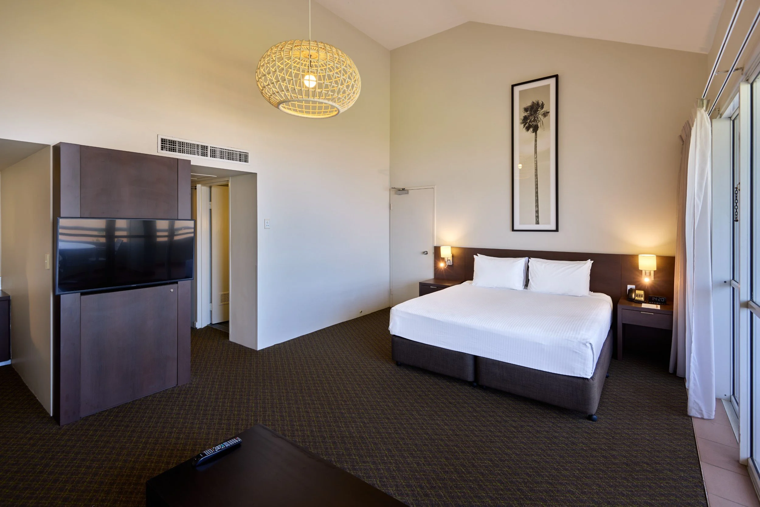 King bed in a room with tall ceilings and designer light feature (2).jpg