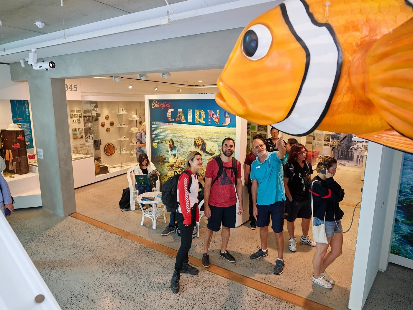 Visitors enjoying a clownfish installation hanging overhead inside Cairns Museum.