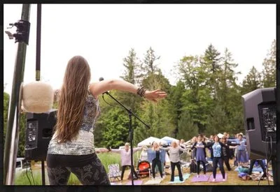 Fifty women follow belly dance instruction from belly dance expert Lara Victoria. They are dancing outside in a meadow at the Gathering of the Goddesses, a summer event.