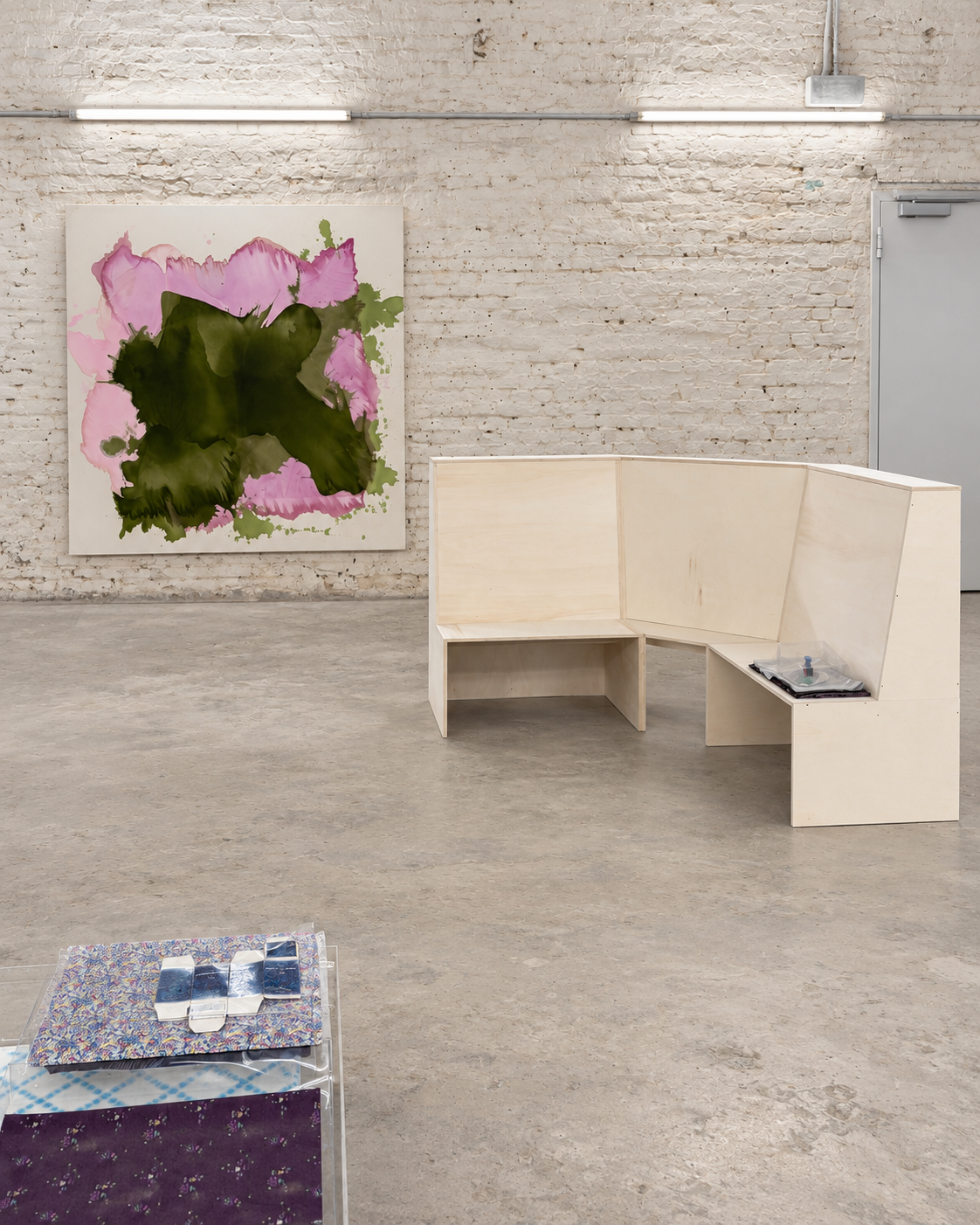 Installation view of IST showing Marie Birkedal’s Hope is the thing with feathers mounted on the brick wall, with another artwork positioned in the foreground.