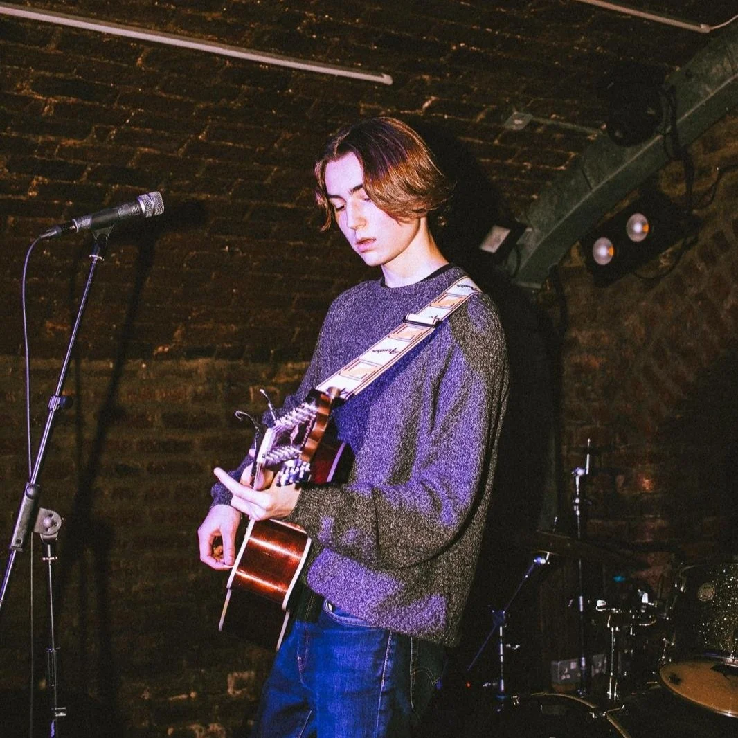 John Denton plays his acoustic guitar on stage.