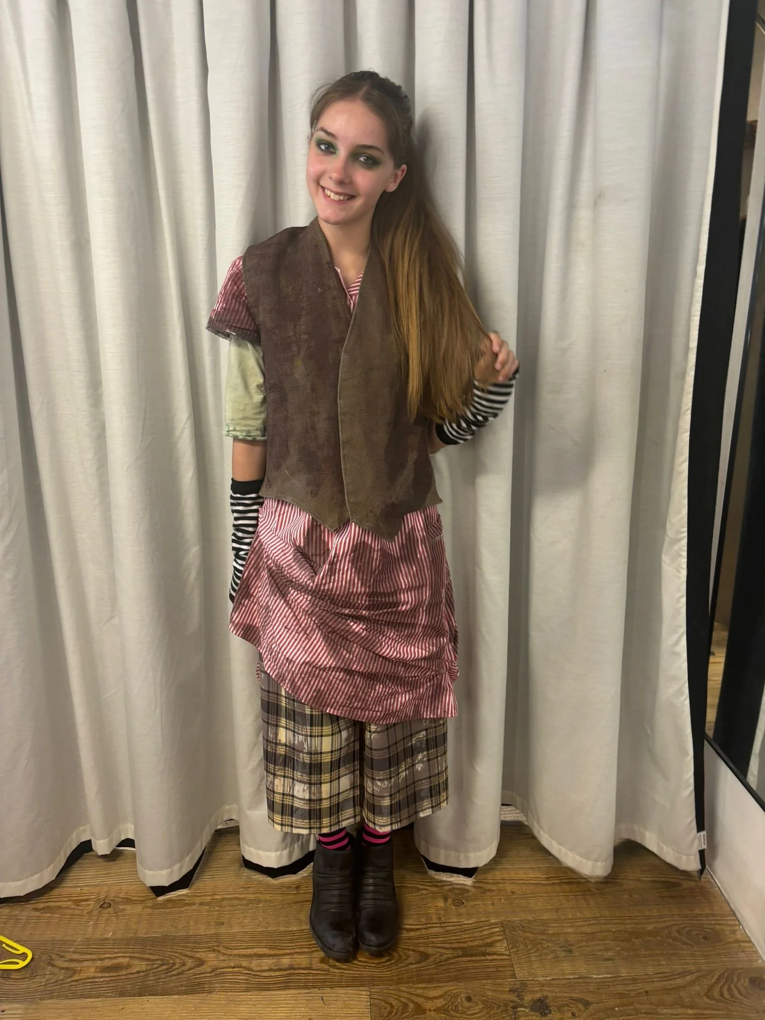 Young teen, Eva Johnson, smiling at the camera. She is dresses in scruffy punk attire for her role in When We Strike.