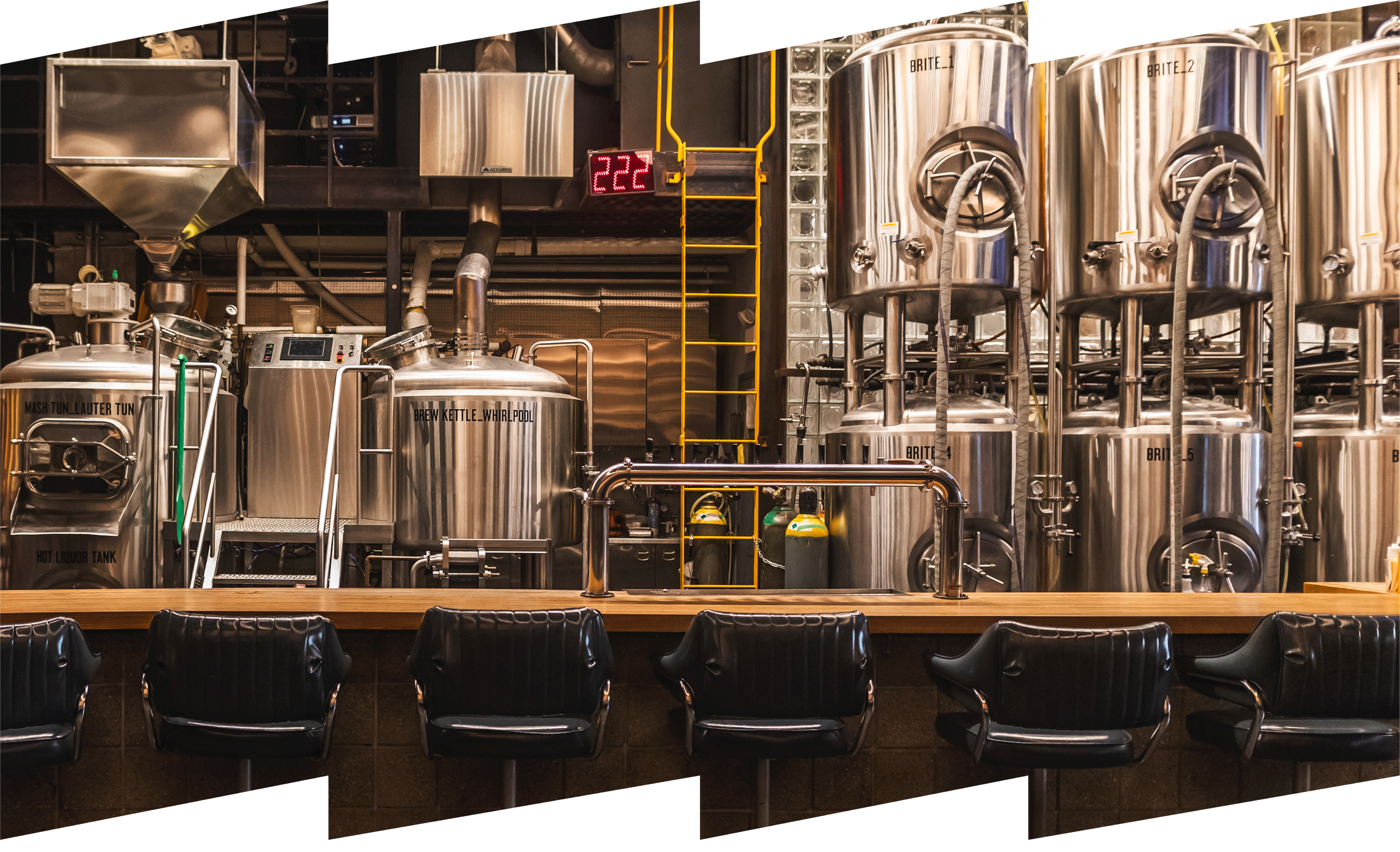 Interior of a brewery with stainless steel tanks and blue bar stools