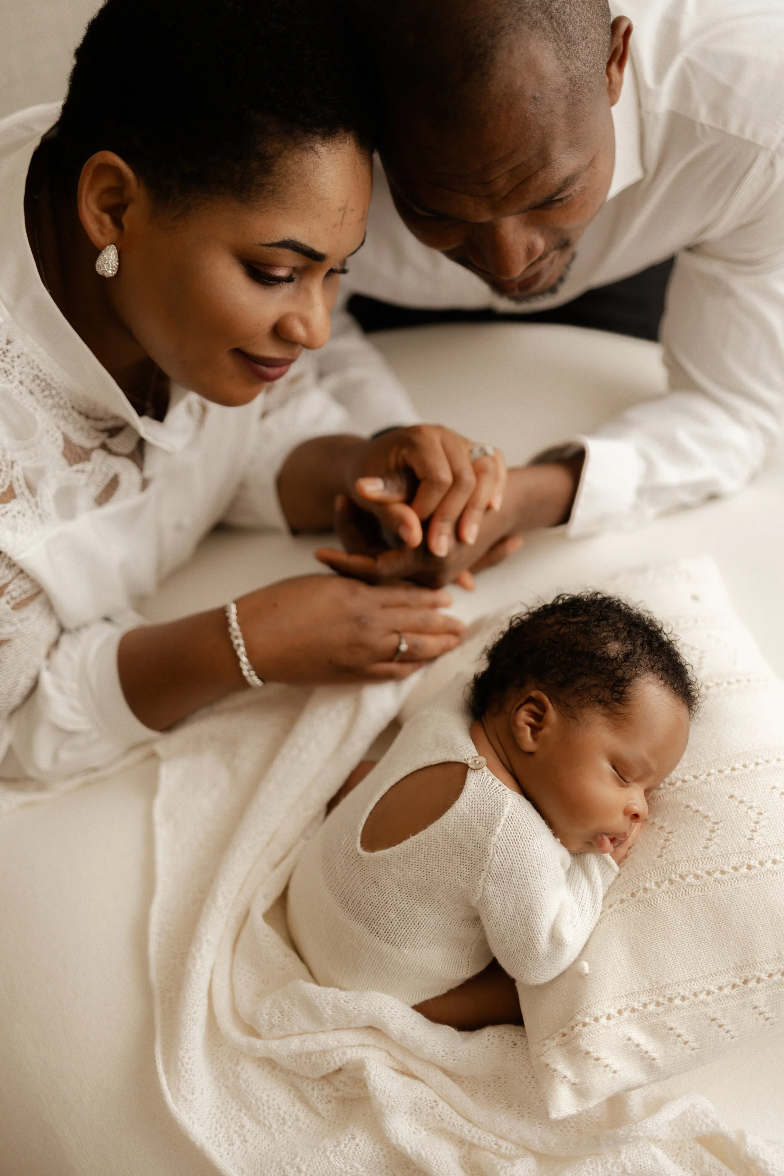 mother and father holding hands whilst looking at how perfect their newborn son is 