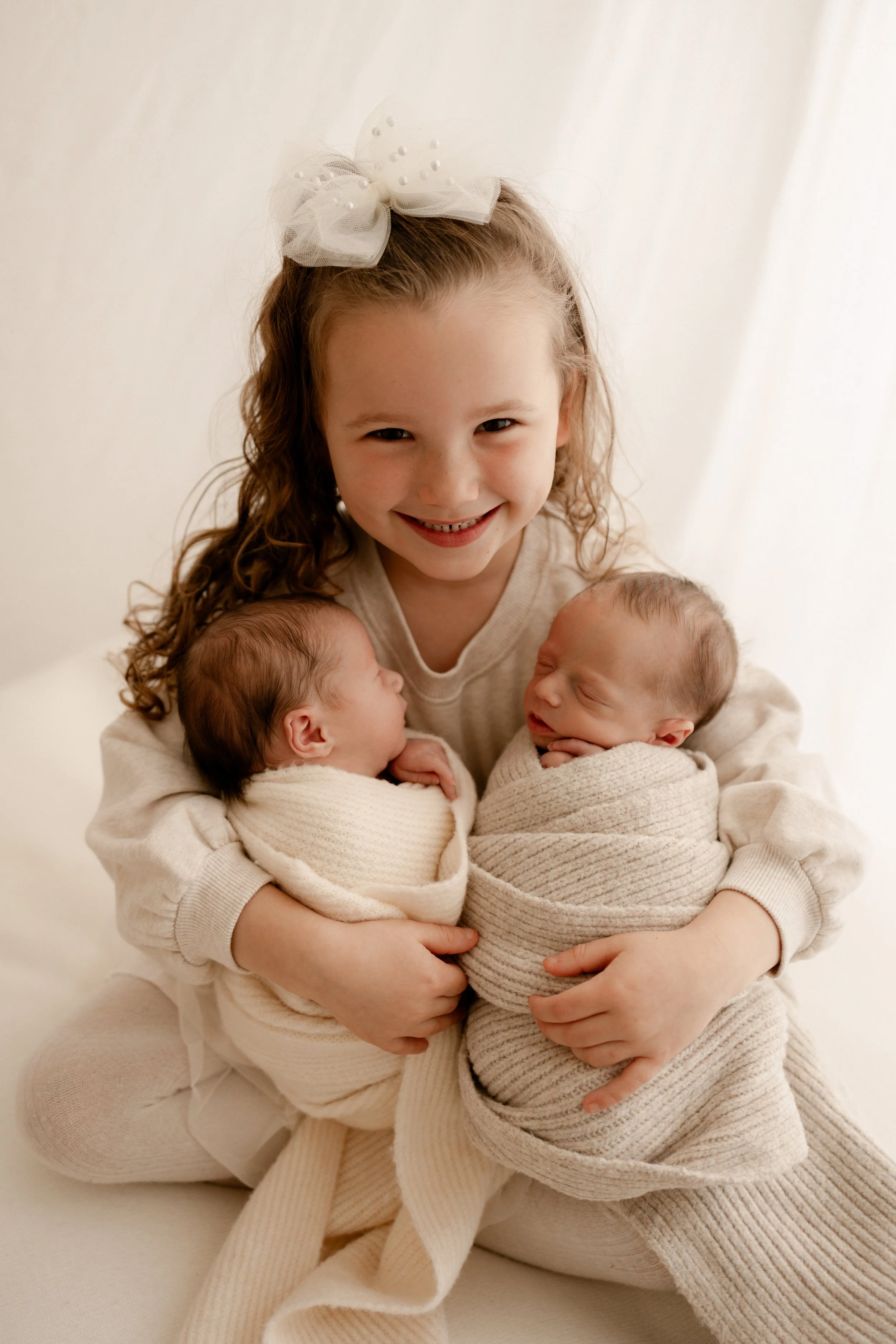 sister snuggling her newborn twin siblings