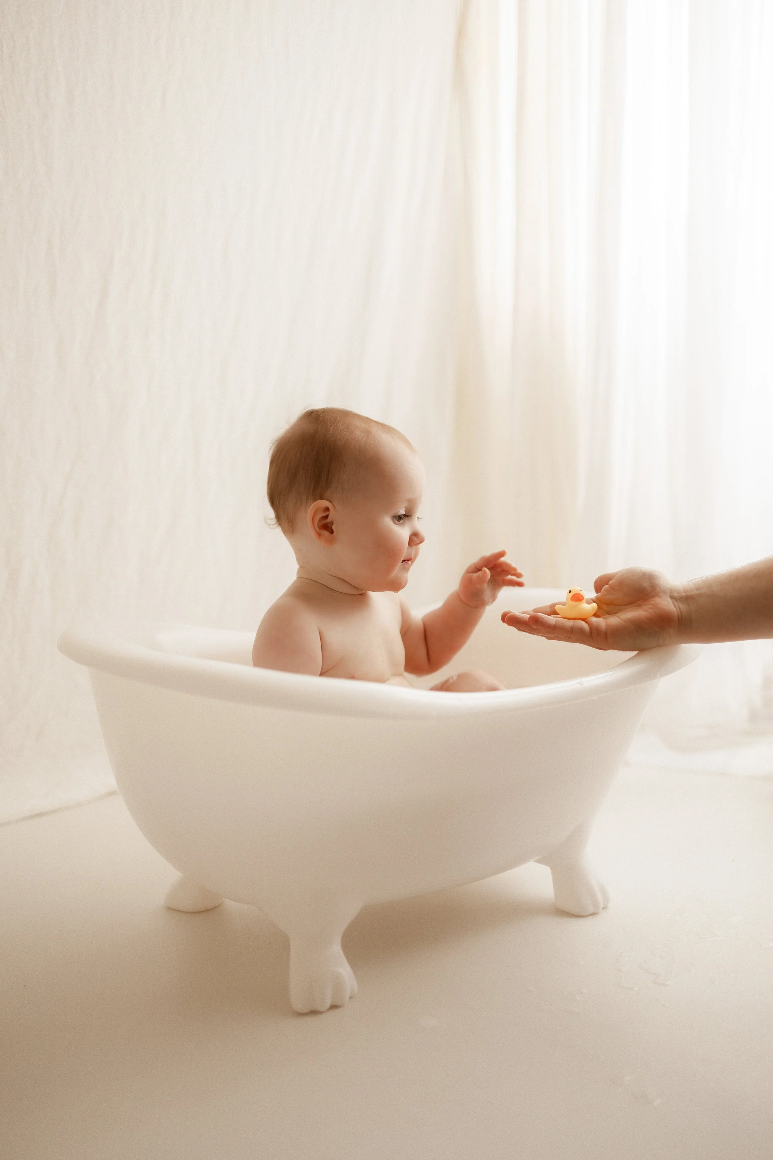 baby in bath tub with rubber duck