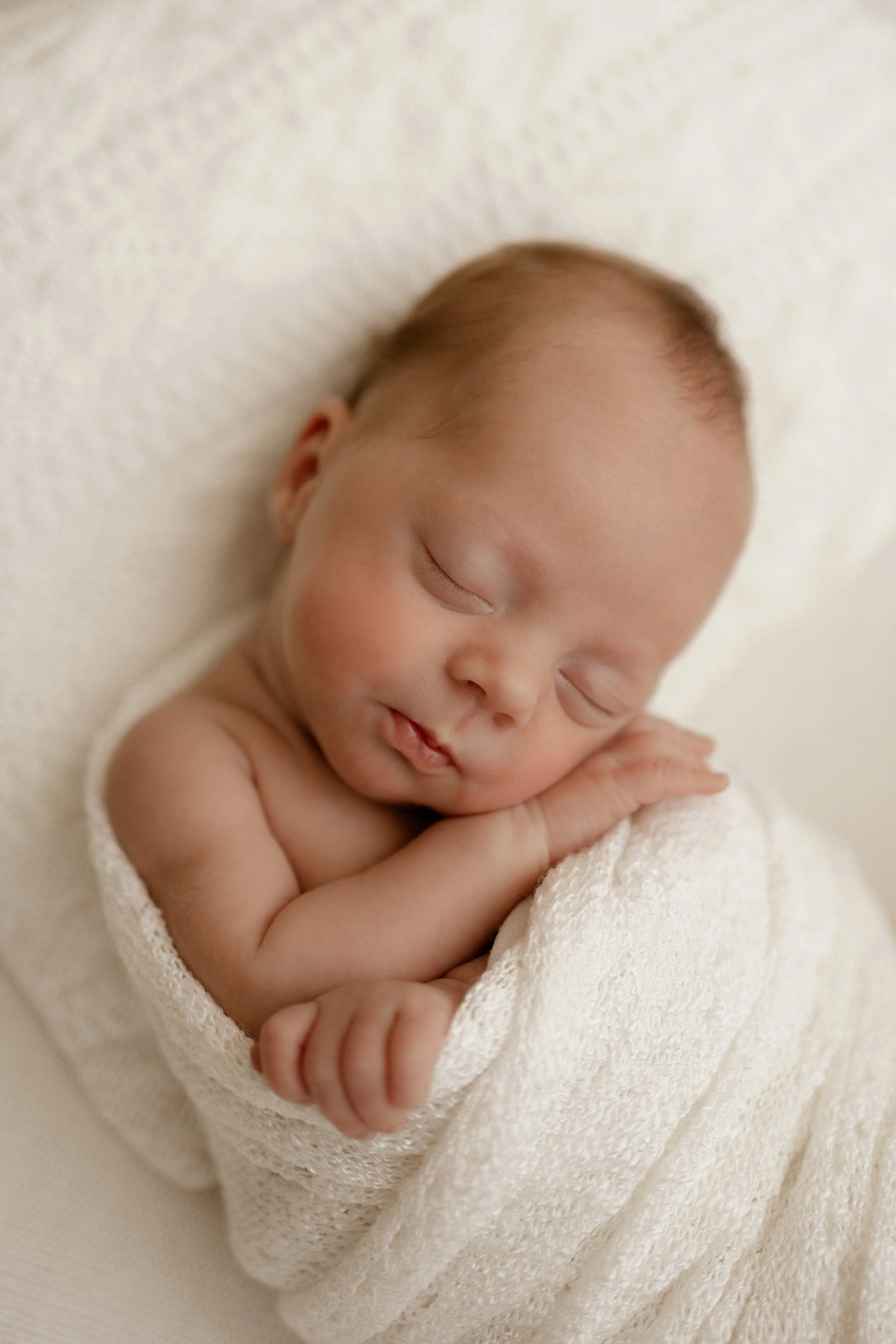 peaceful newborn sleeping in white wrap