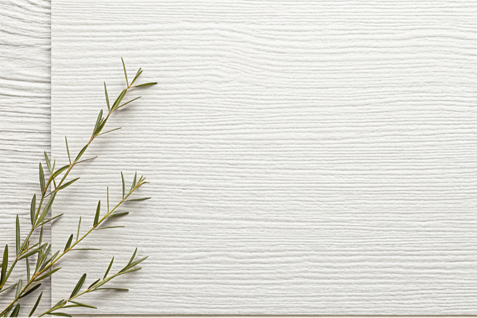Close-up of a sprig of green herb, possibly rosemary, placed on light wooden background.