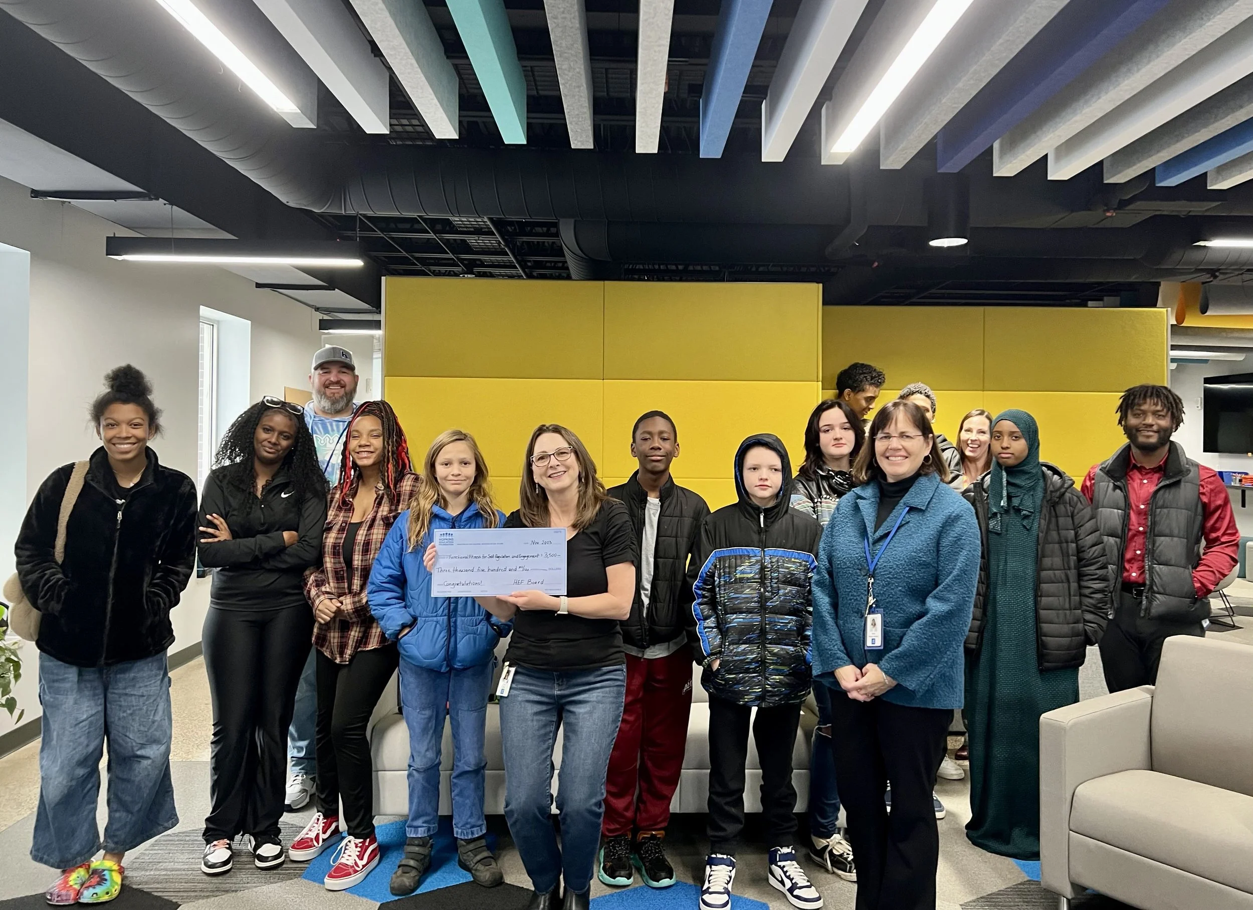 Group of students and adults with large grant check