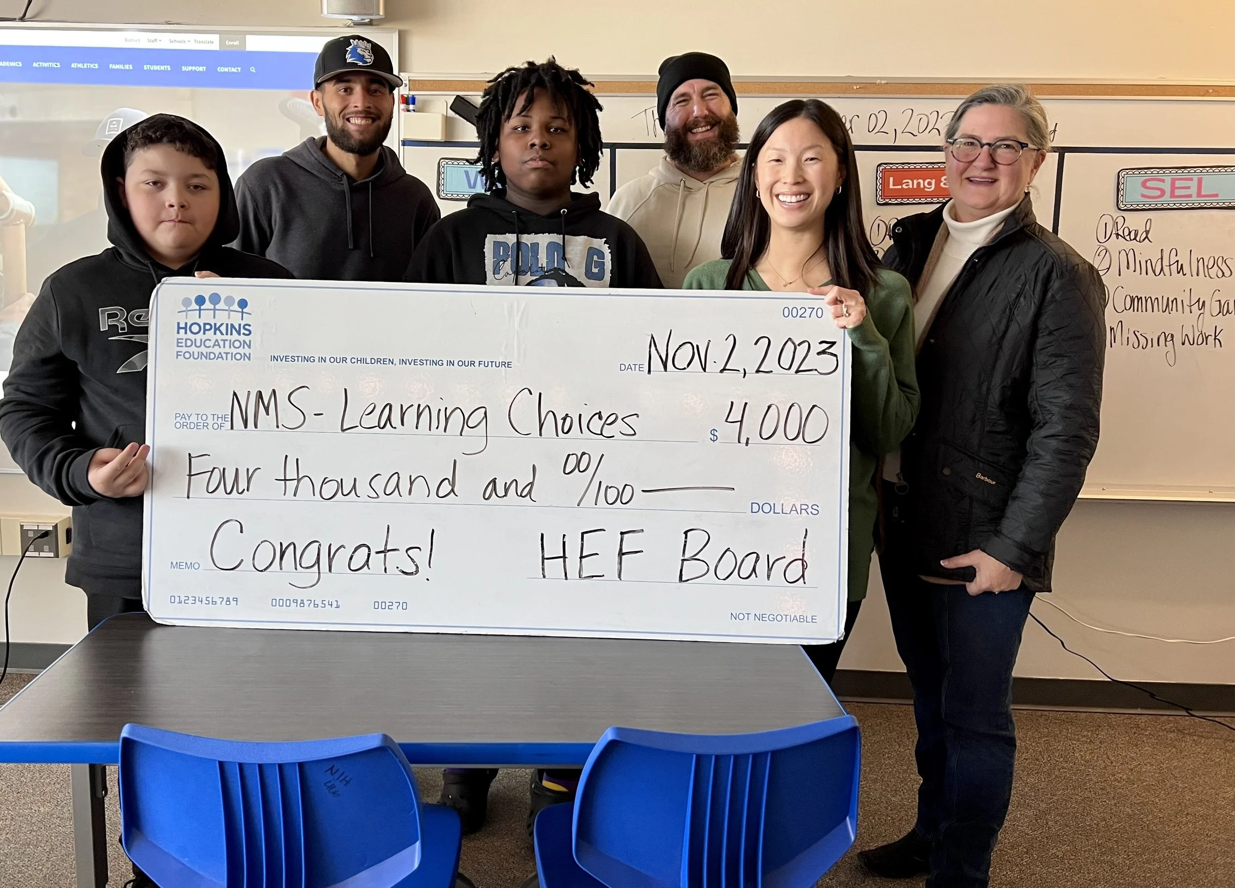 Group of students and adults with large grant check