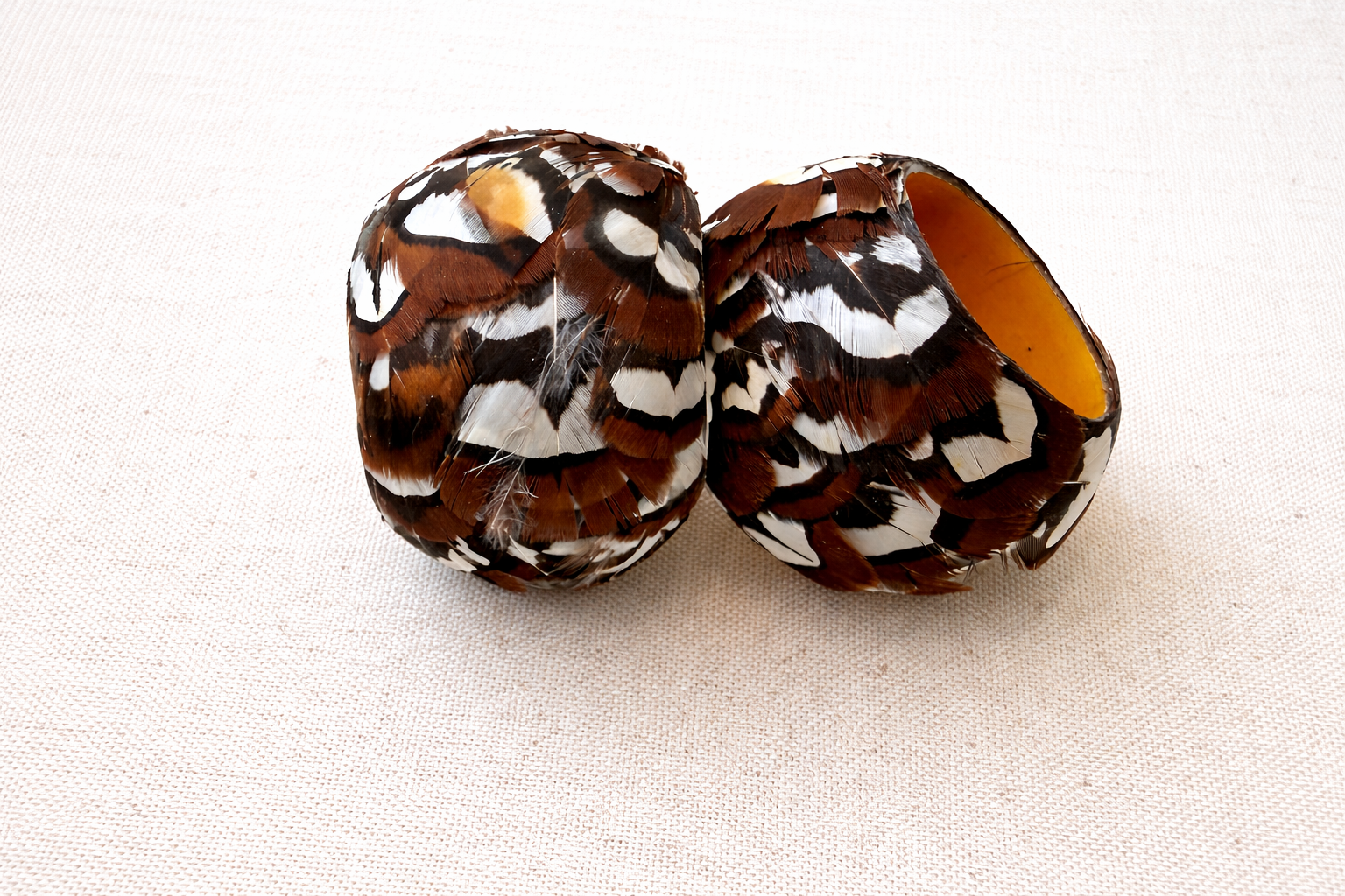 Feather-wrapped wooden bowls on fabric.png