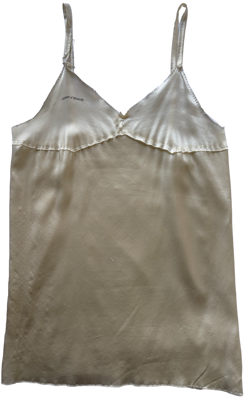 A cream-colored satin camisole with thin straps and a ruffled trim along the neckline, labeled with the brand 'conor o'driscoll' inside.
