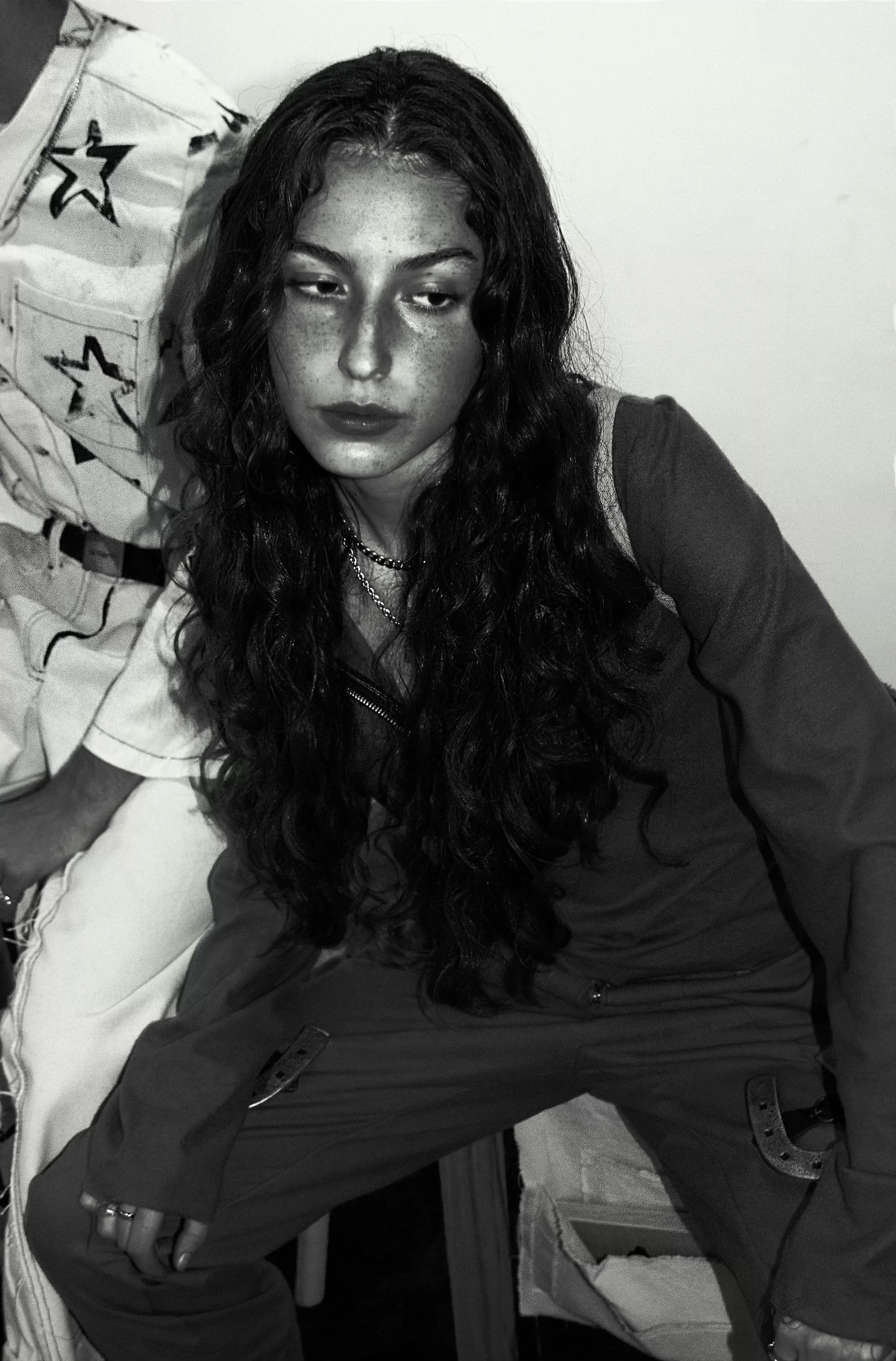 A woman with long, curly hair and freckles, wearing a dark jacket, is looking down with a neutral expression. conor o'driscoll