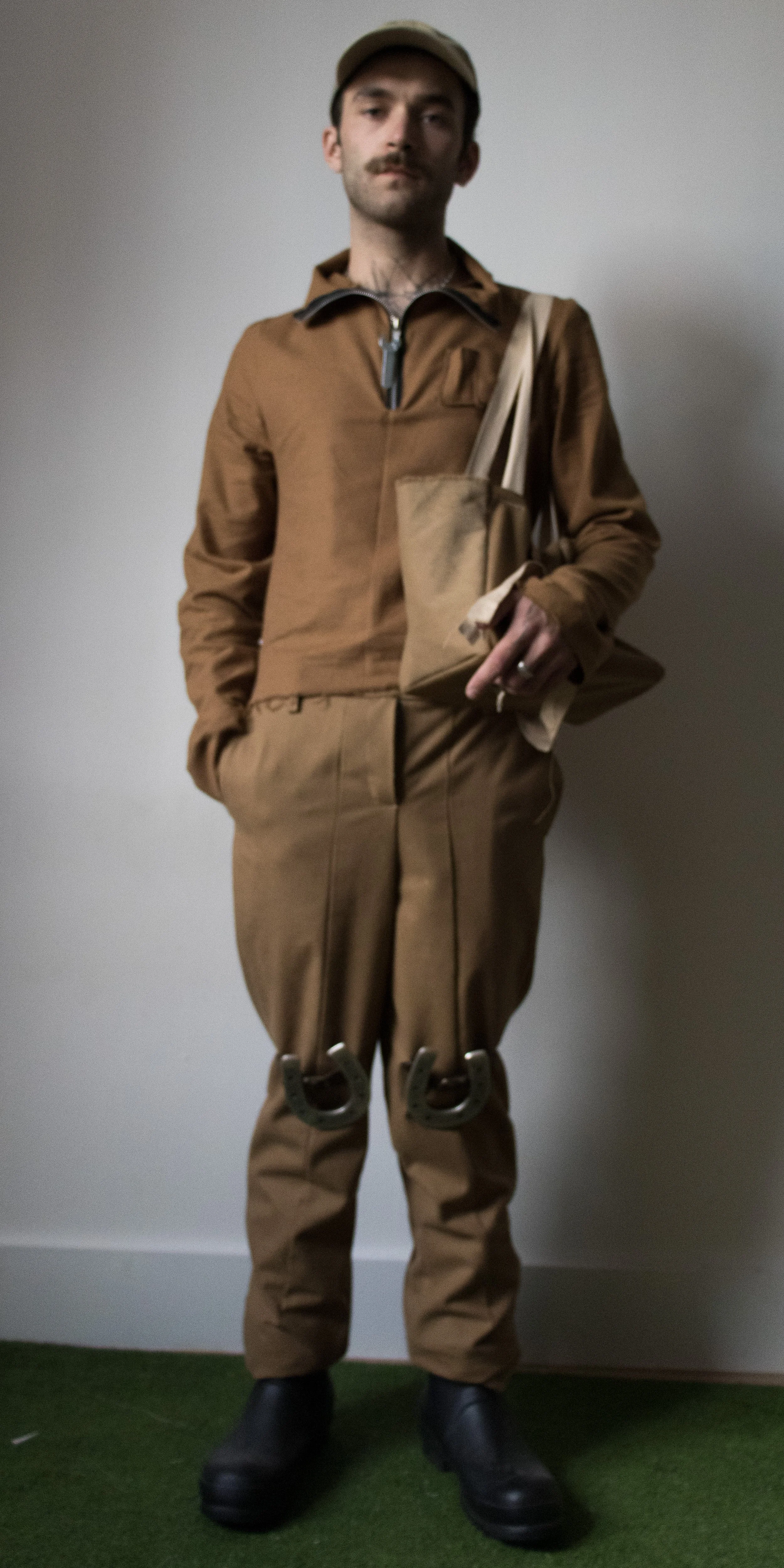 grant philips wearing horseshoe riding pants flannel top with wrench pull  suede work bag by conor odriscoll defective workwear collection 2022