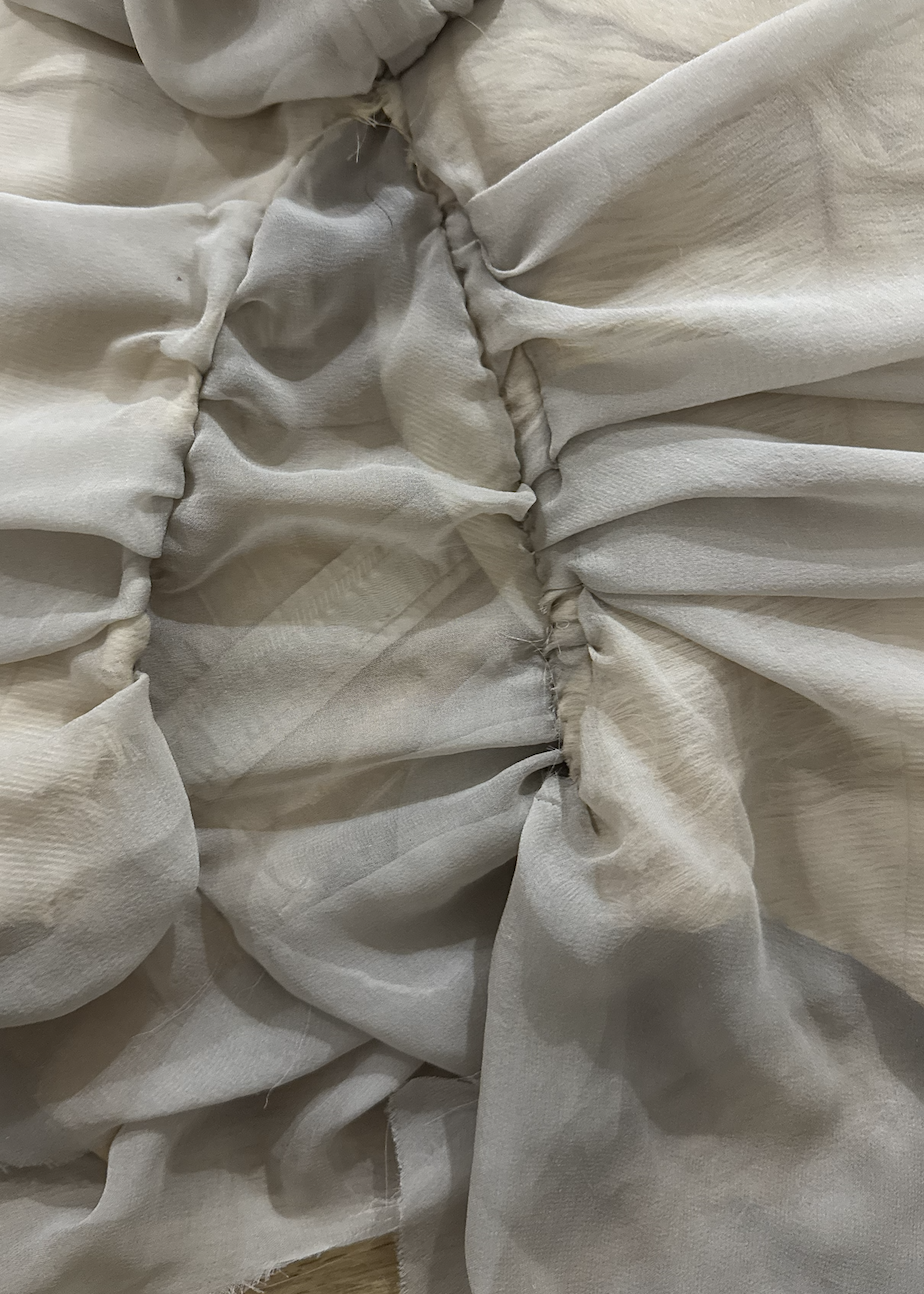 CONOR ODRISCOLL FOR VETTESE. S26 NYFW Close-up of white fabric with gathered, ruched sections, possibly part of a curtain or clothing
