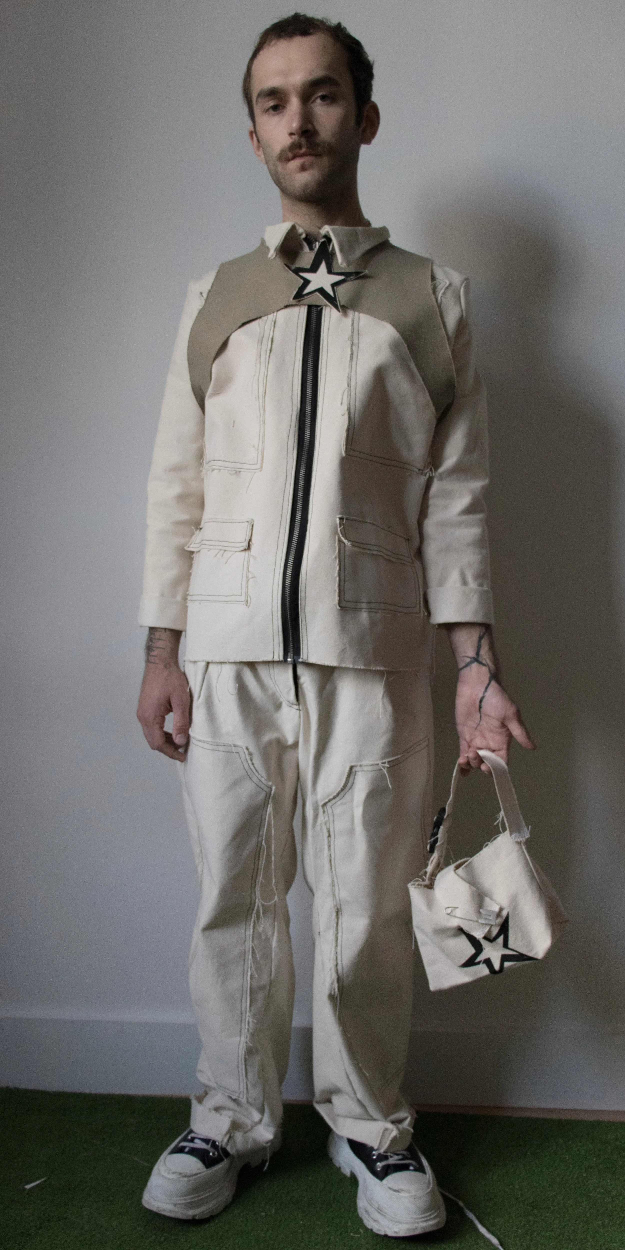 grant philips wearing canvas jacket canvas pants and star harness with star canvas print bag by conor odriscoll defective workwear collection 2022
