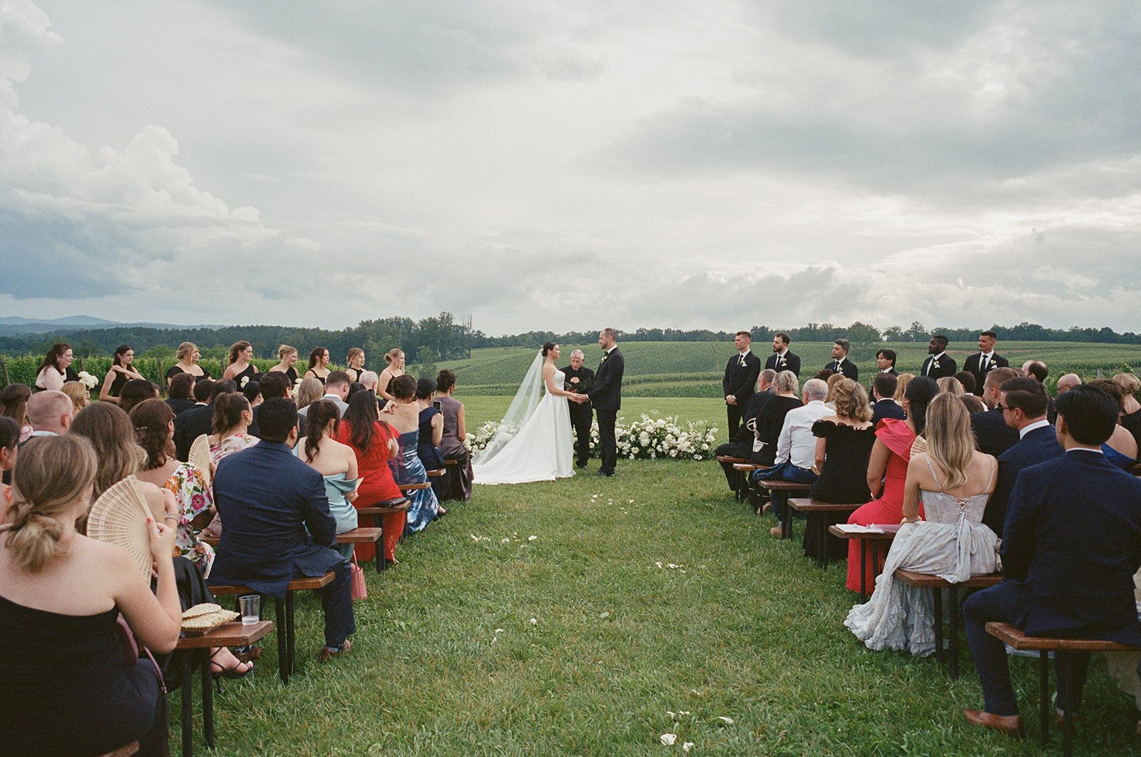 BRIDE GROOM WEDDING CEREMONY GROUNDED GROUND FLORAL ARCH WHITE FLOWERS STONE TOWER WINERY FIELDS VIRGINIA