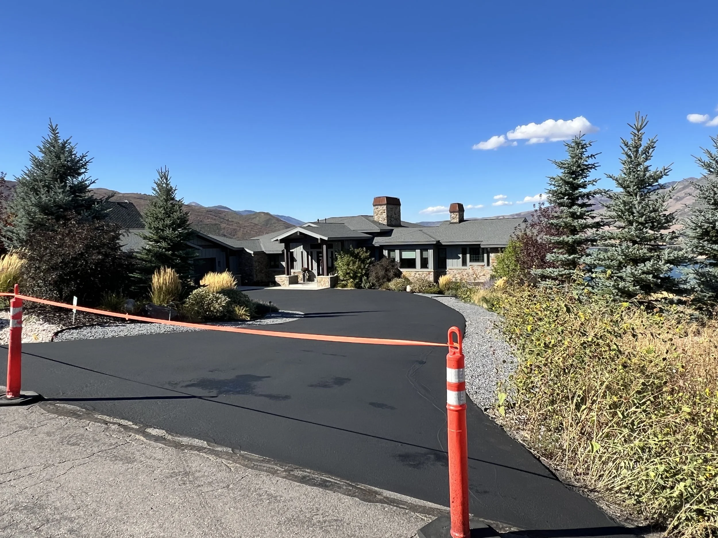 Newly sealed residential asphalt driveway in Northern Utah with clean edges and professional curing setup, installed by Slate Canyon Asphalt for long‑lasting performance in freeze–thaw conditions.