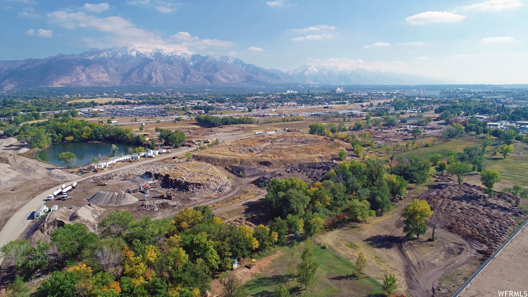 Small pond, farm property, and gravel pit in West Haven Utah with Malan Peak visible in the far distance, near residential and commercial areas served by asphalt paving, repair, and maintenance services.