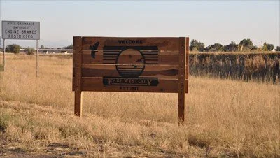 Farr West Utah wooden city sign just off 2000 West near Smith Family Park and the Smith & Edwards Country Boy Store, serving nearby residential and commercial areas with asphalt paving, repair, and maintenance services.