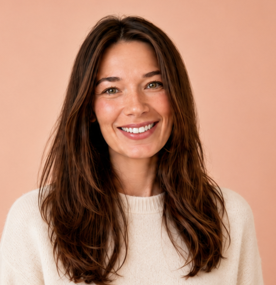 Daria Sur | Instructional Designer | Learning Experience Designer |  A woman with long, wavy brown hair smiling at the camera against a peach-colored background, wearing a light-colored sweater.
