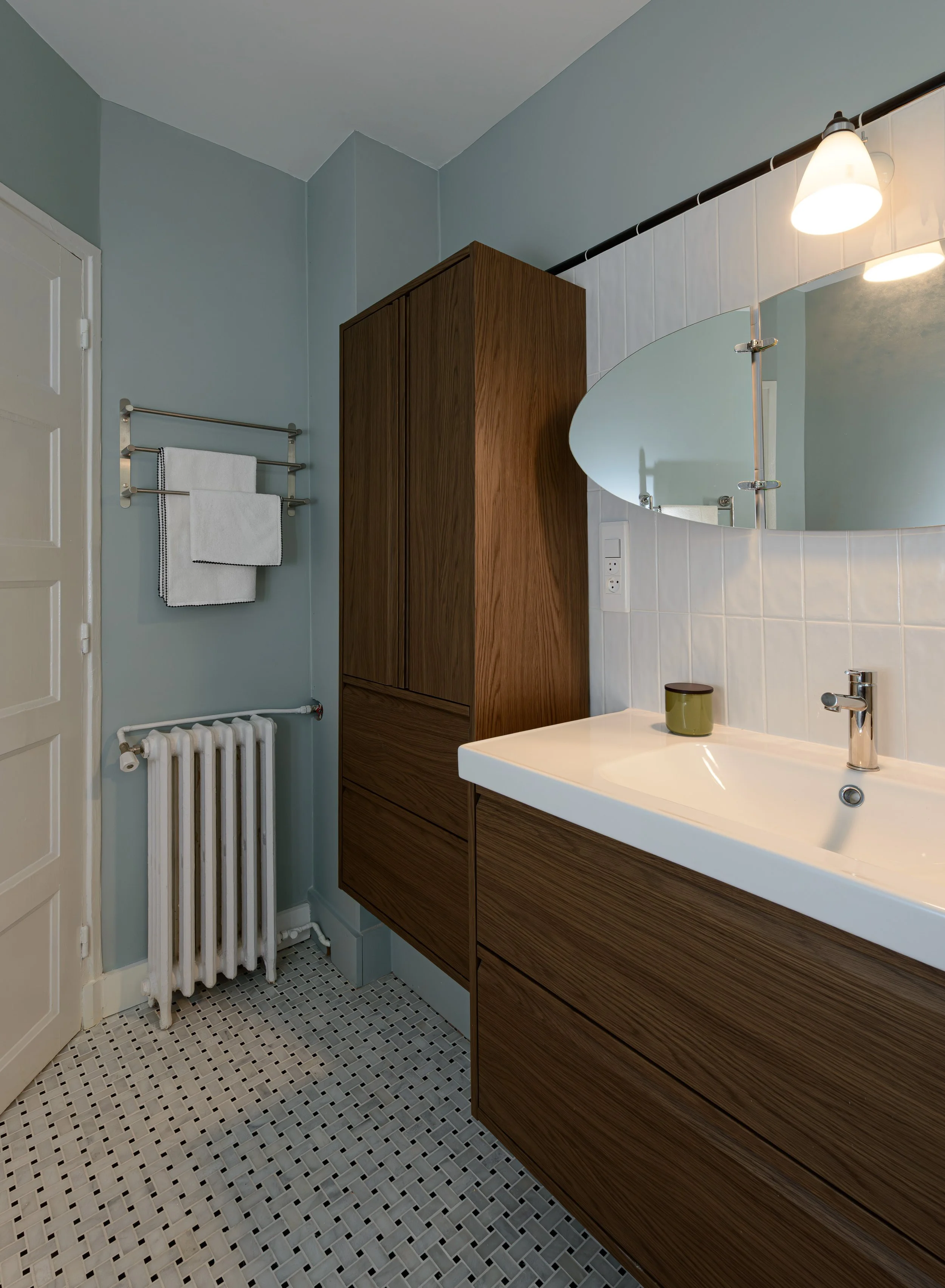 La rénovation de la salle de bain intègre également la récupération d’un radiateur en fonte, restauré pour conserver son authenticité. Ce détail apporte du caractère à la pièce, tout en s’harmonisant avec l’ambiance rétro et élégante de l’ensemble.