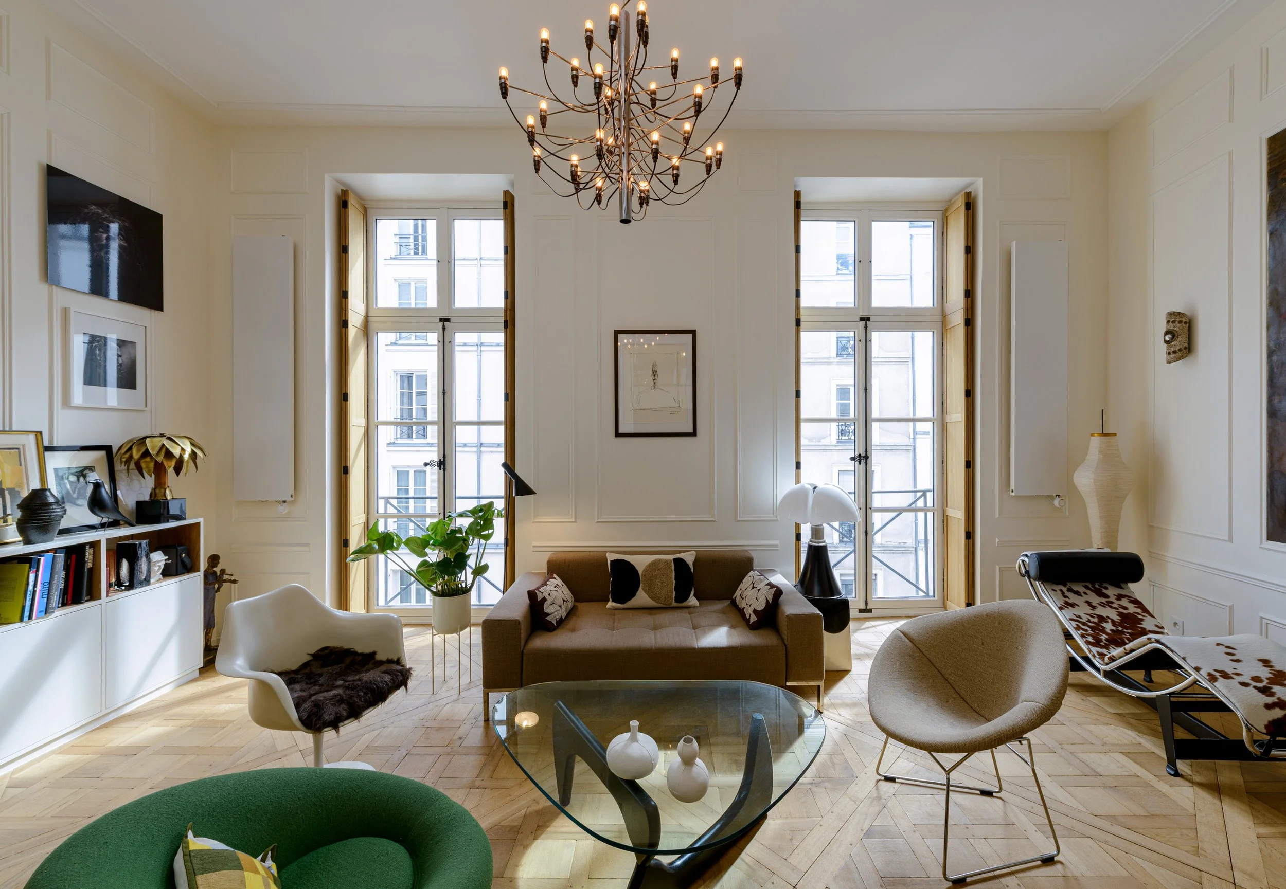 Les nouvelles portes-fenêtres en bois, accompagnées de volets intérieurs en chêne et de crémones noires, améliorent le confort tout en respectant le caractère de l’appartement.