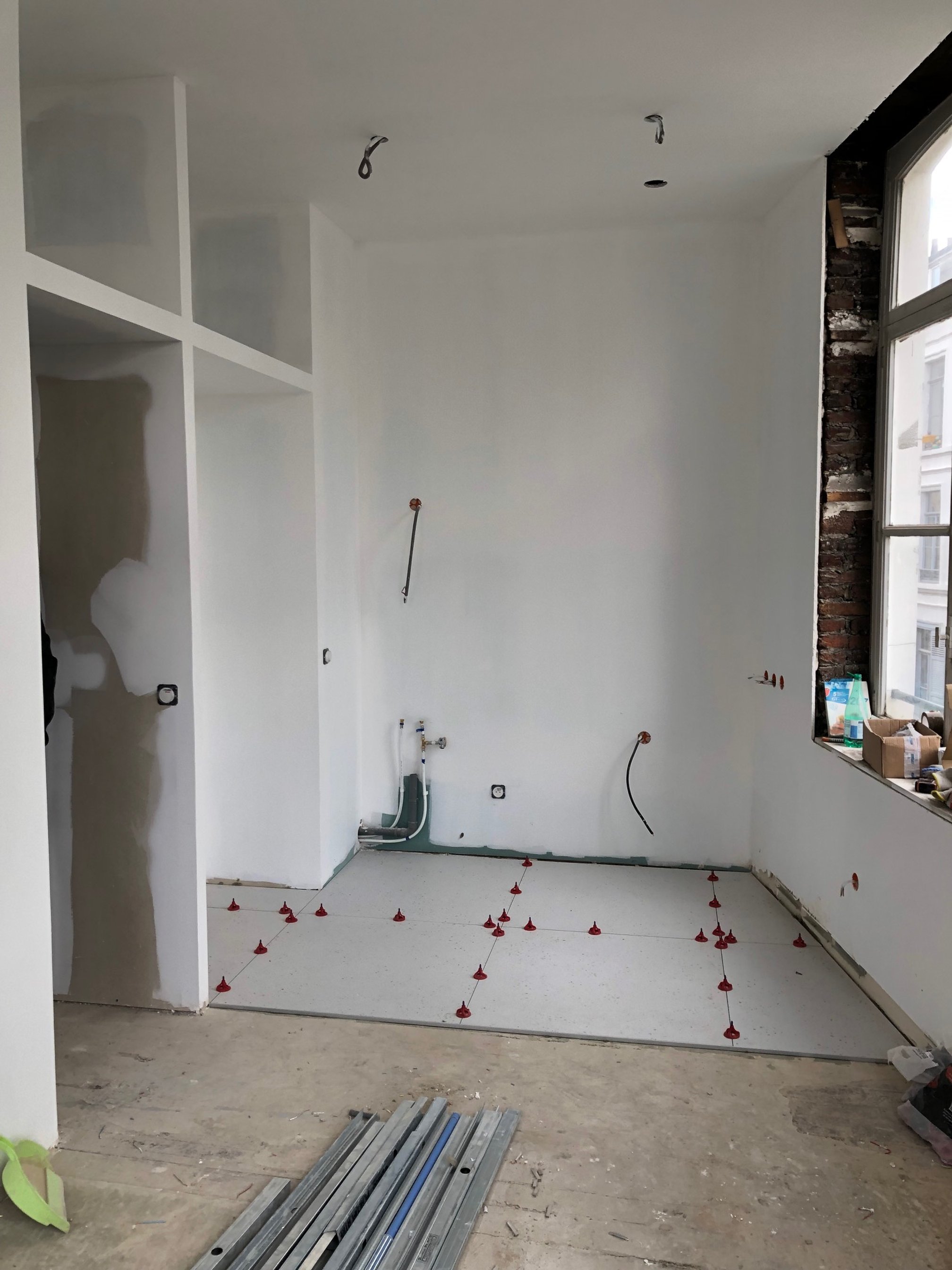 Côté cuisine, construction de la paroi épaisse dissimulant l'électroménager et pose du nouveau carrelage au sol.