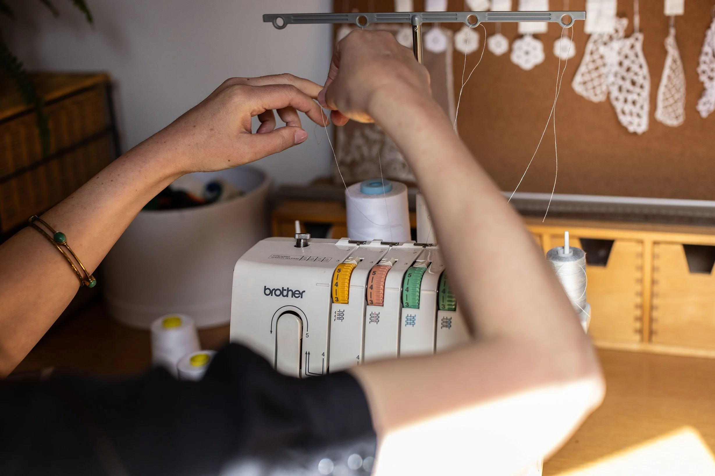Bridal designer threading a serger sewing machine with threads