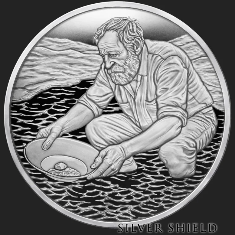A minted silver proof coin with an elderly man with a beard, kneeling in water and holding a dish with an object and some grains on it. The background features mountains and water. The image includes the text 'Silver Shield' at the bottom.