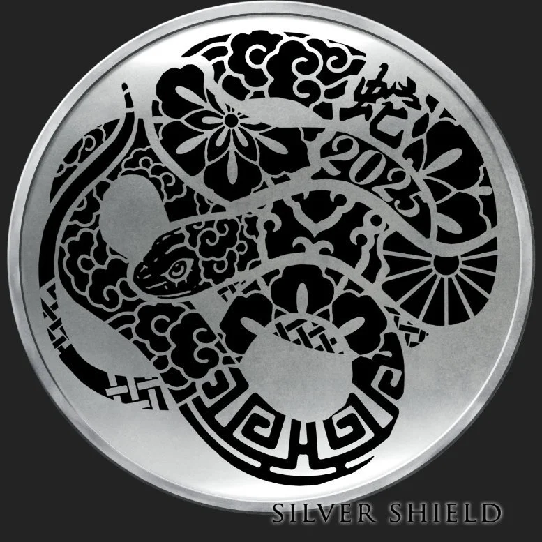 A minted silver proof coin with an intricate black design featuring a snake, floral patterns, and geometric shapes, with the words 'Silver Shield' at the bottom.