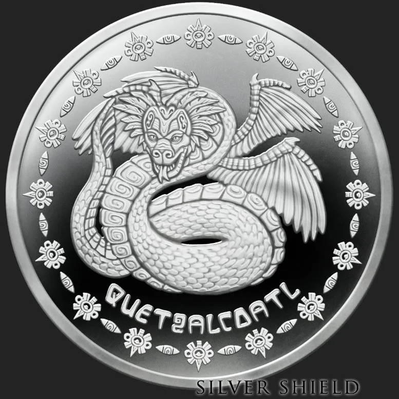 A silver coin featuring a detailed dragon with lion-like face, wings, and a coiled body. The background has decorative floral patterns and the words 'QUE TAL CATRL' and 'SILVER SHIELD'.