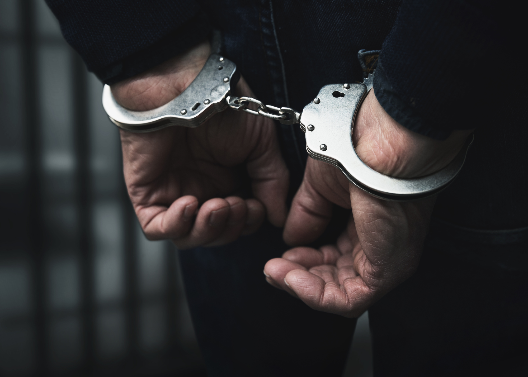 Hands secured behind a person's back in handcuffs